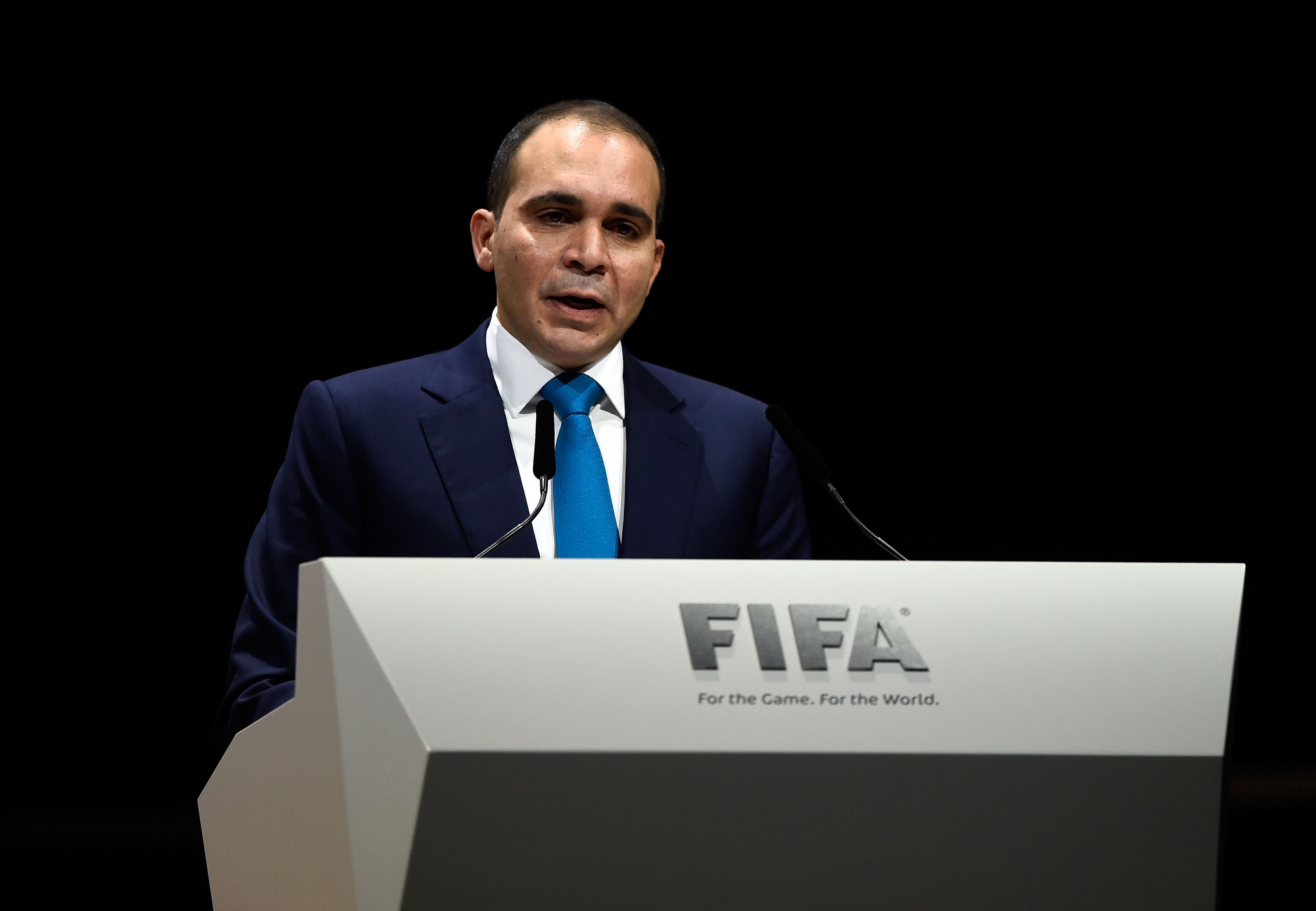 Ein Mann im Anzug spricht bei einem FIFA-Kongress an einem Rednerpult mit FIFA-Logo.