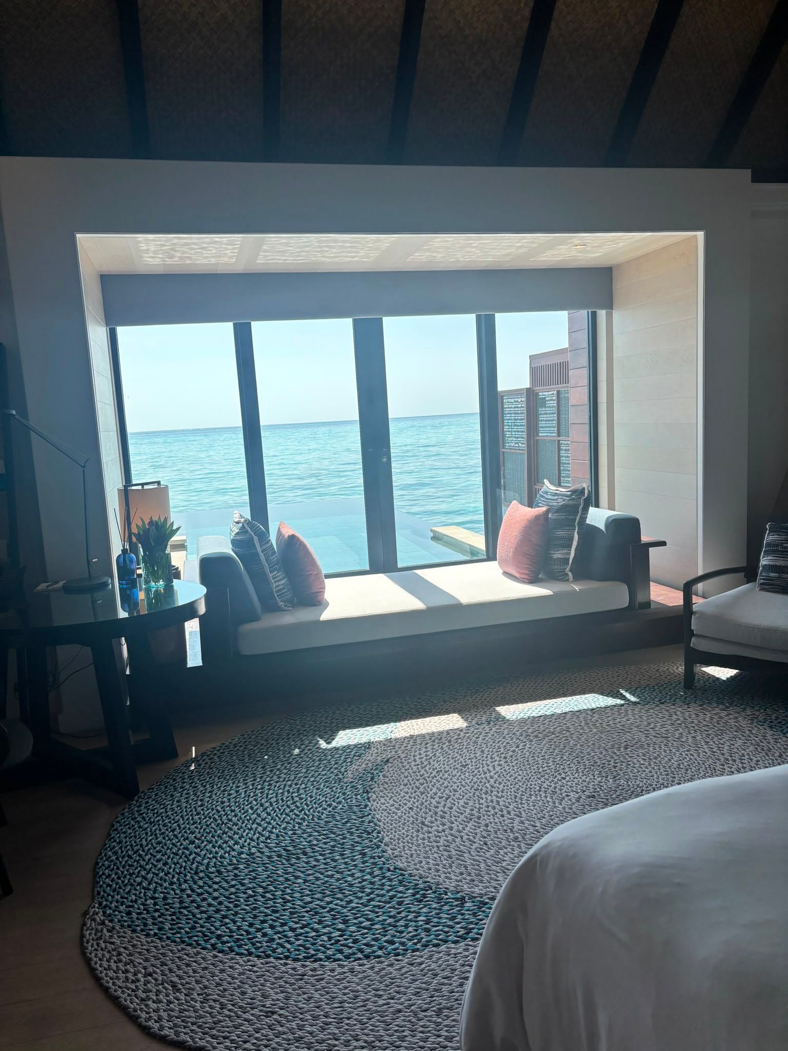 Modernes Zimmer in einem Überwasser-Bungalow mit Meerblick durch große Panoramafenster.