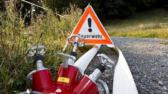 Feuerwehr-Schlauchverteiler und Warnschild "Feuerwehr" auf einem Feldweg.