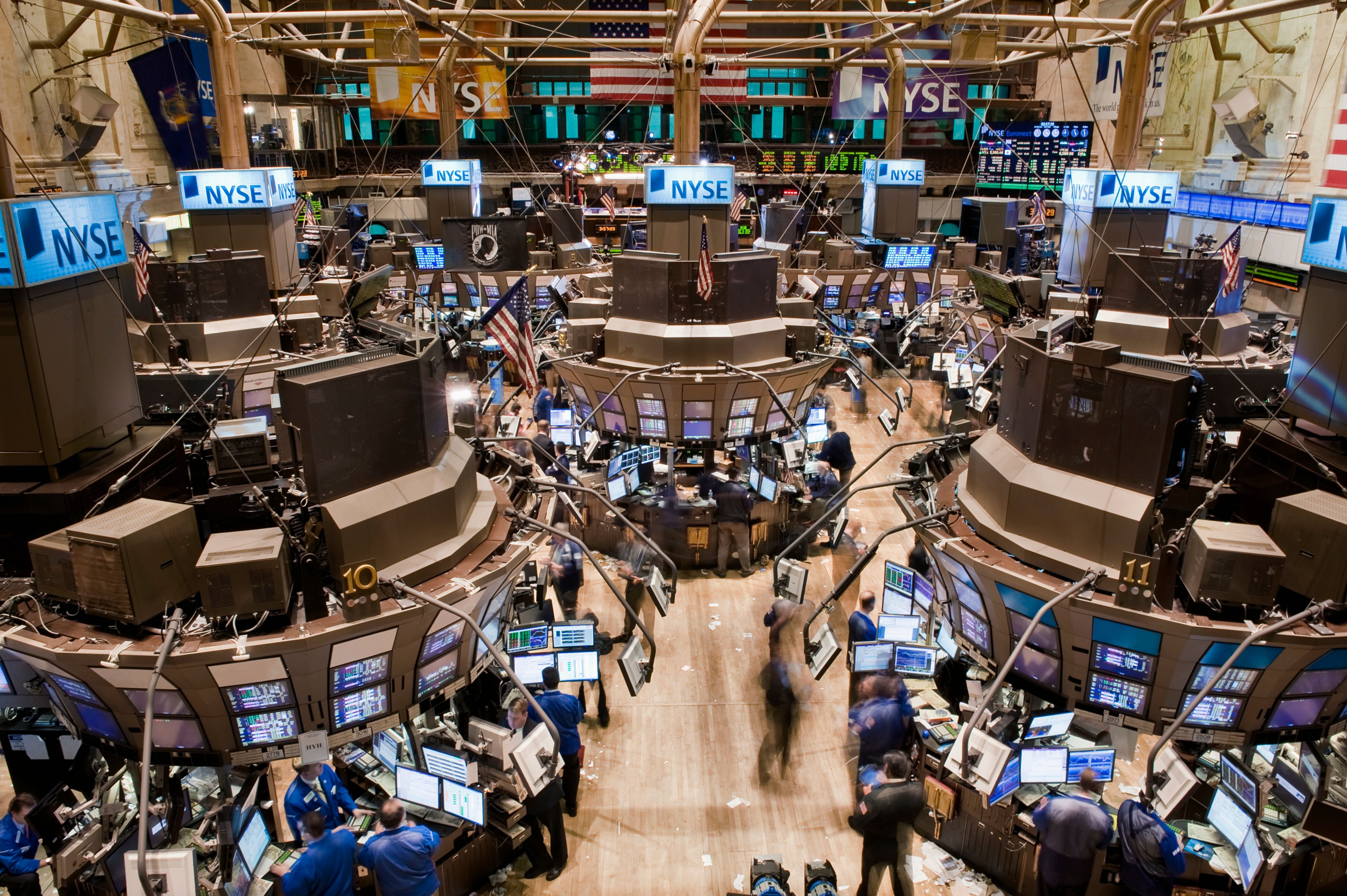 Blick auf das Parkett der New Yorker Börse mit zahlreichen Bildschirmen und wenigen Händlern.