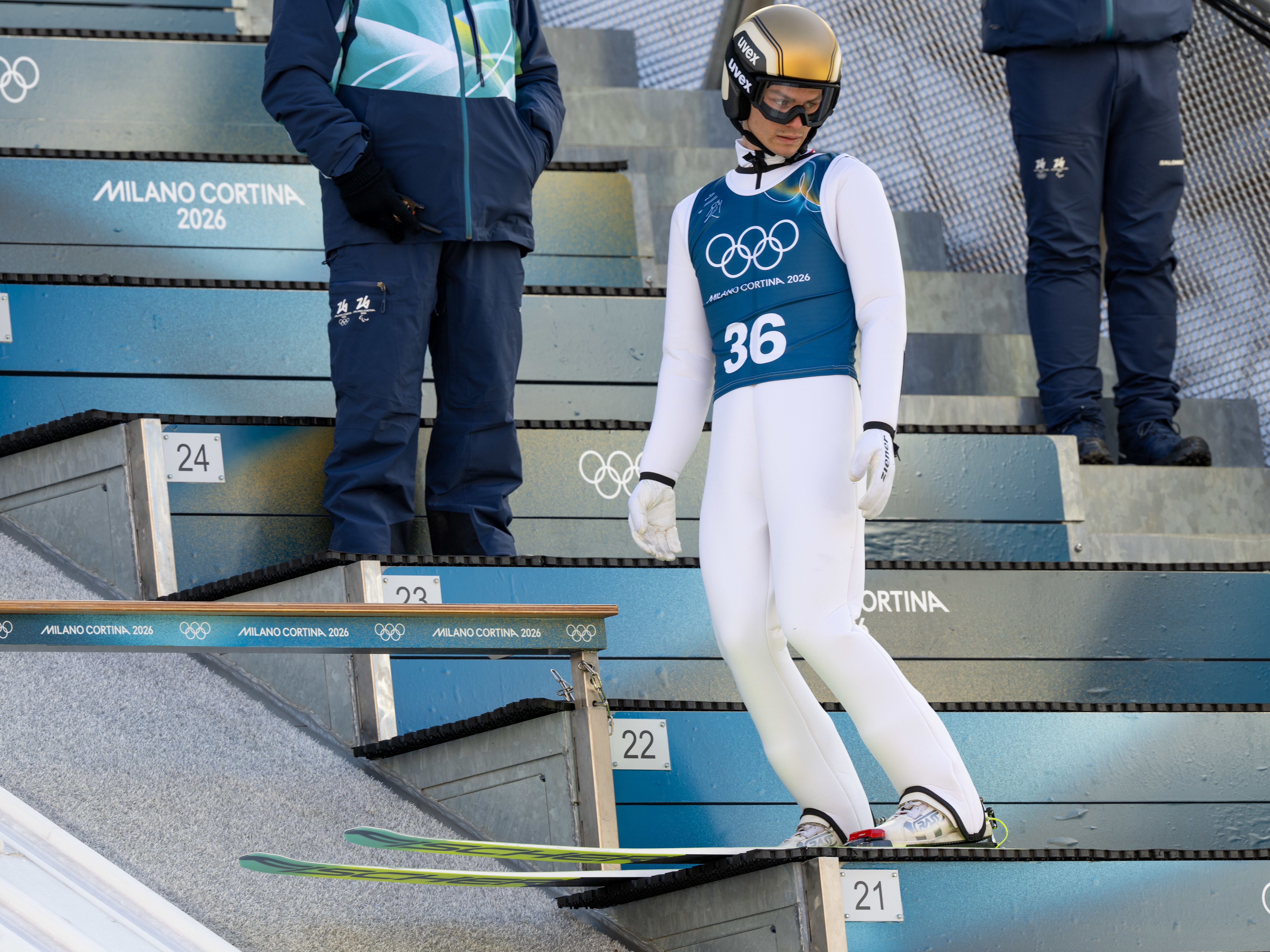 Ein junger Mann beißt auf eine Medaille und trägt eine Winterjacke sowie eine Mütze mit Österreich-Logo.