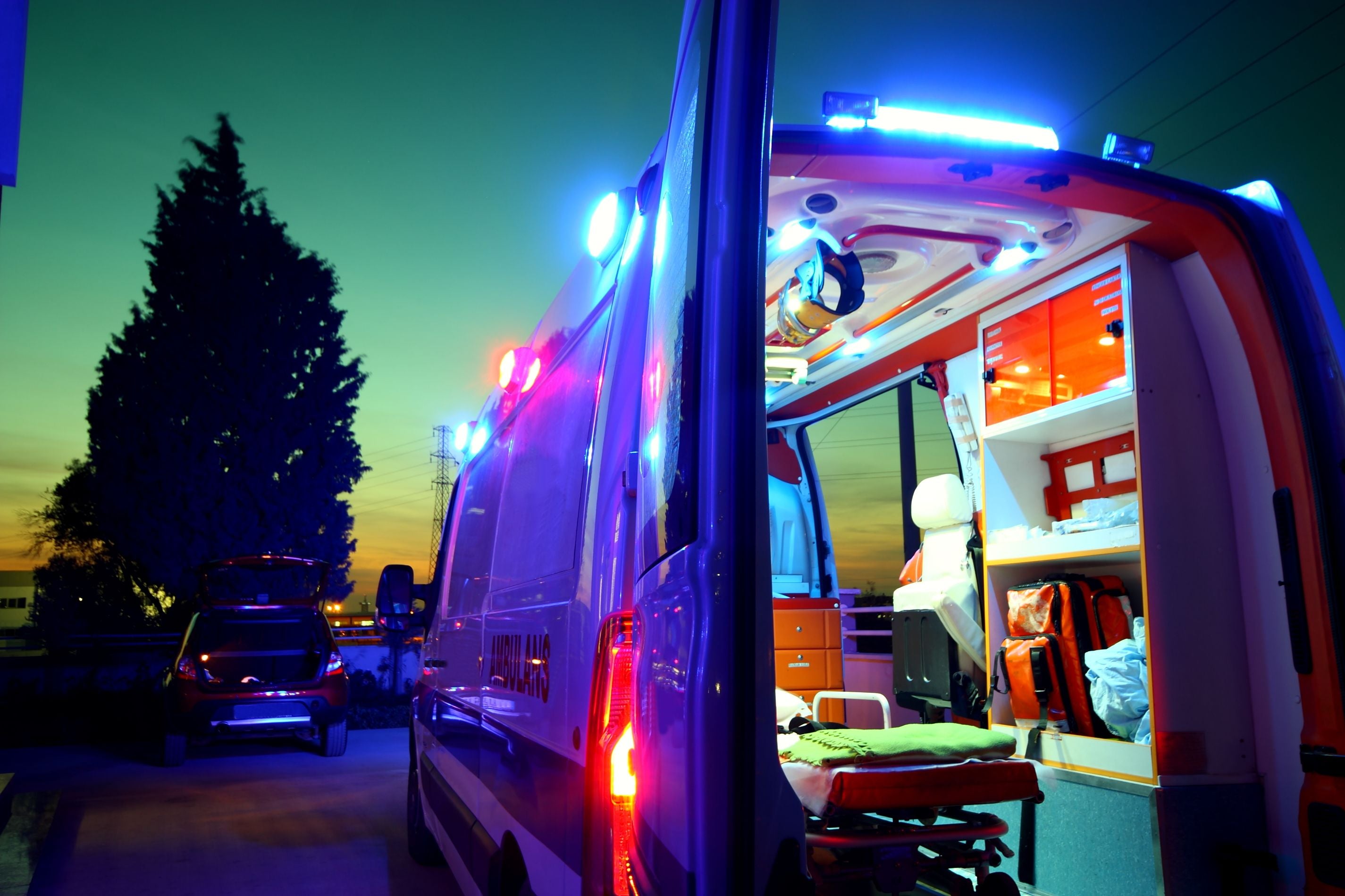 Geöffneter Rettungswagen mit Blaulicht im Sonnenuntergang, Blick ins Innere des Fahrzeugs.