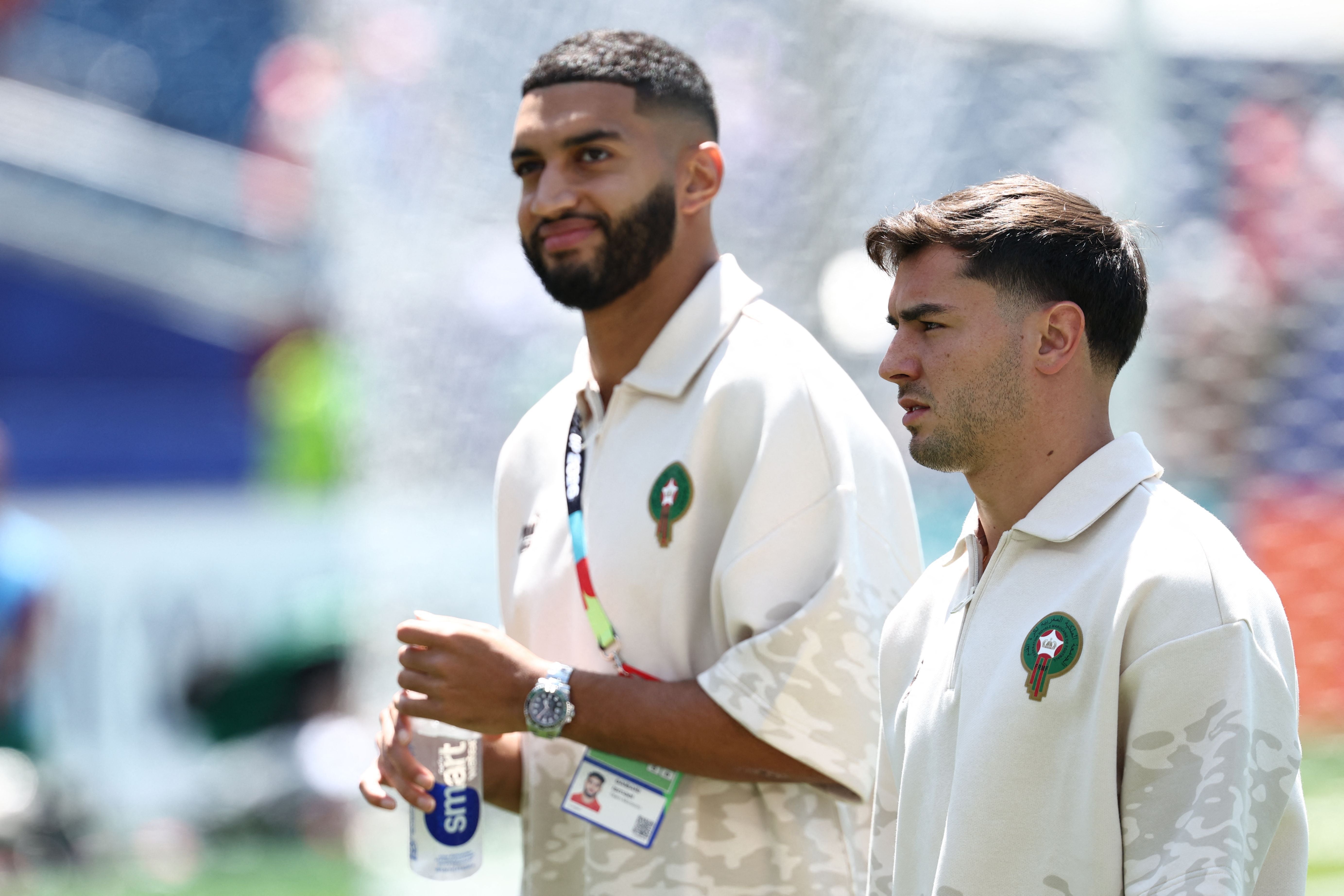 Zwei marokkanische Fußballspieler gehen im Stadion, tragen beige Trainingsshirts.