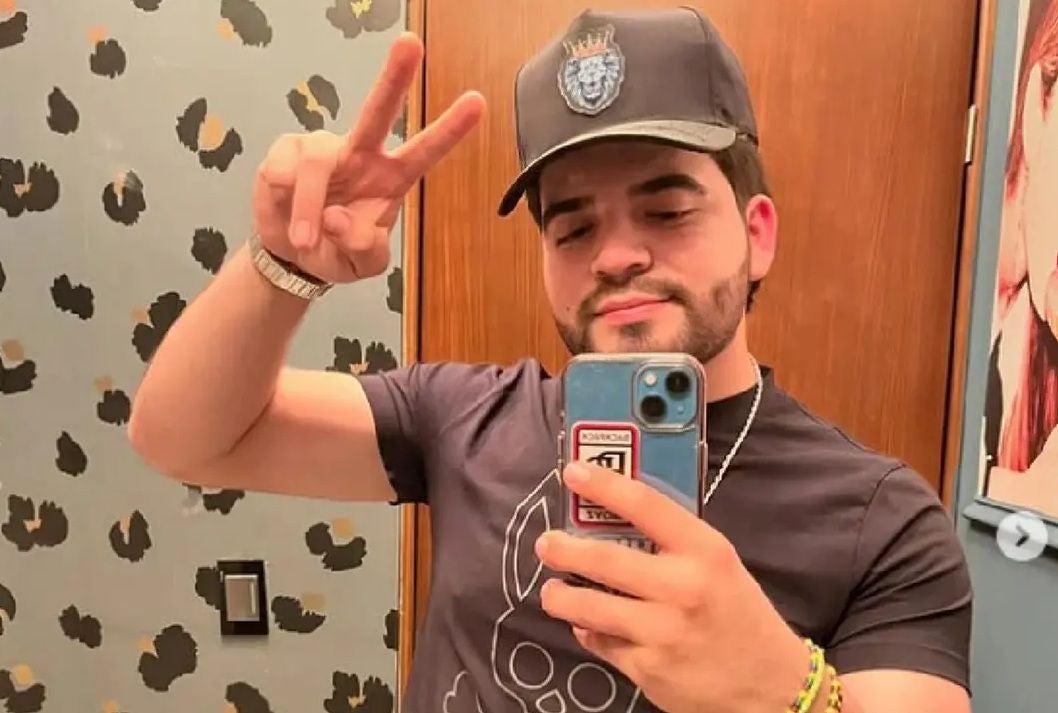 Junger Mann macht ein Selfie im Spiegel und zeigt das Victory-Zeichen mit den Fingern.