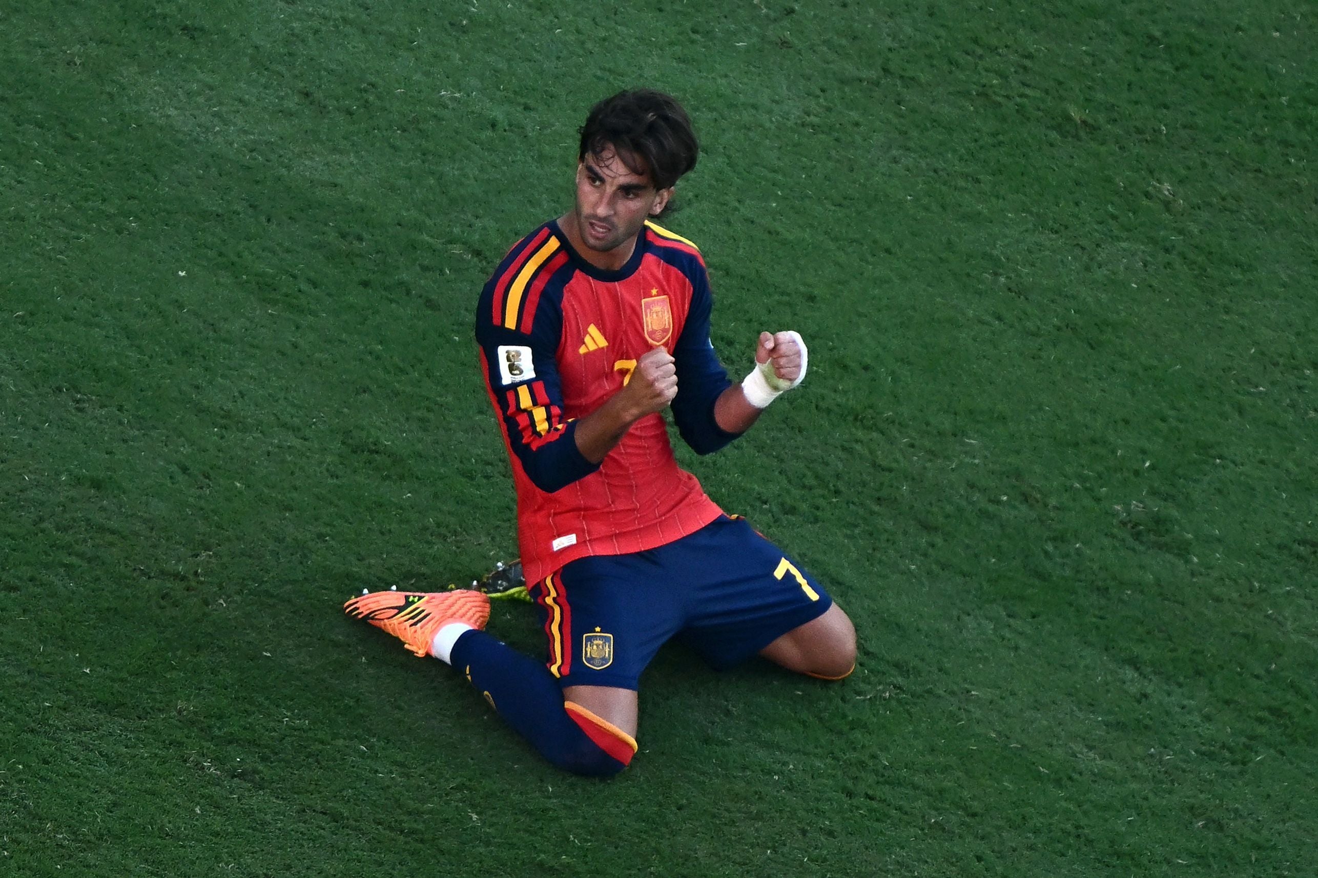 Ein spanischer Fußballspieler kniet jubelnd auf dem Rasen und ballt die Fäuste.