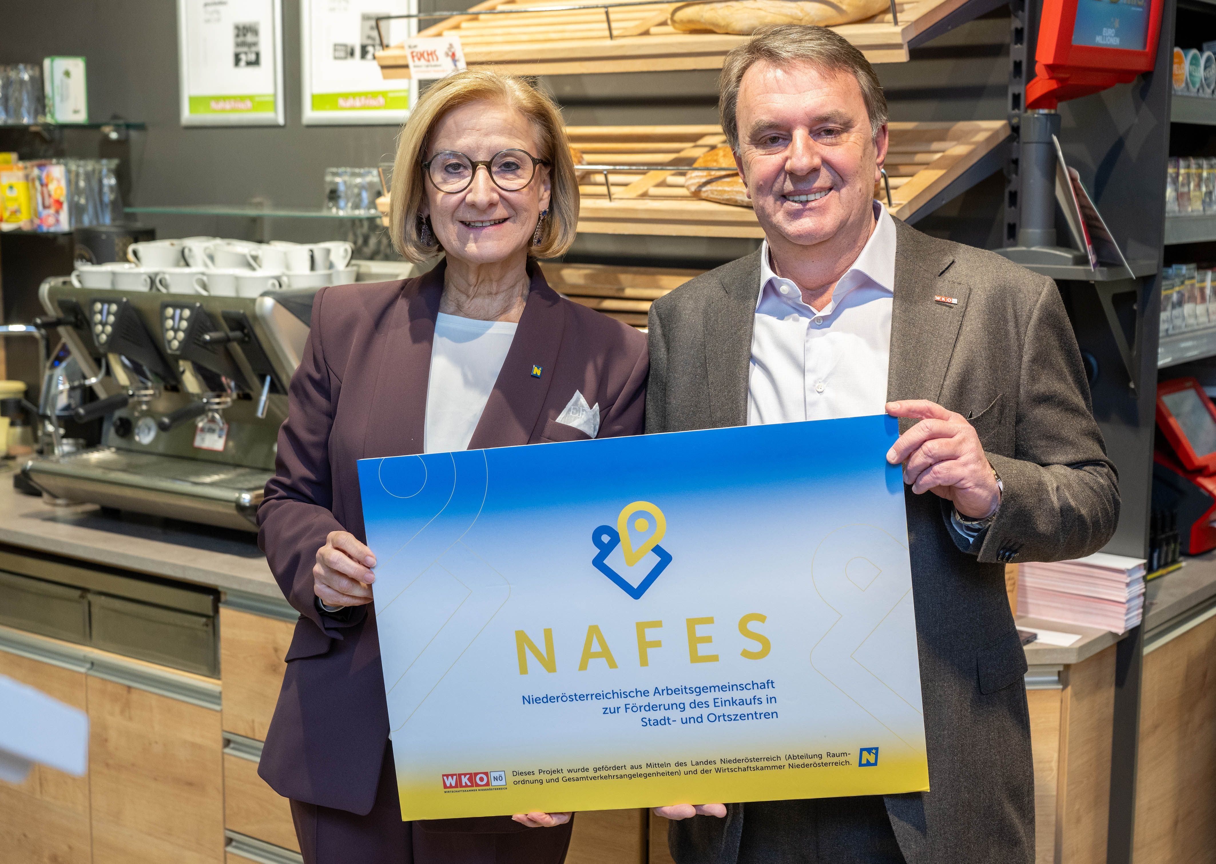 Zwei Personen halten ein Schild mit der Aufschrift "NAFES" in einem Geschäft.