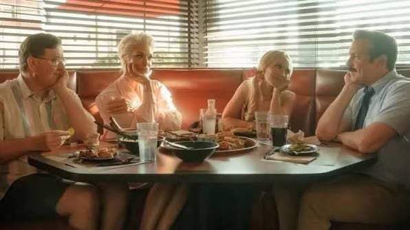 Vier Personen sitzen in einem Restaurant am Tisch und unterhalten sich bei Essen und Getränken.
