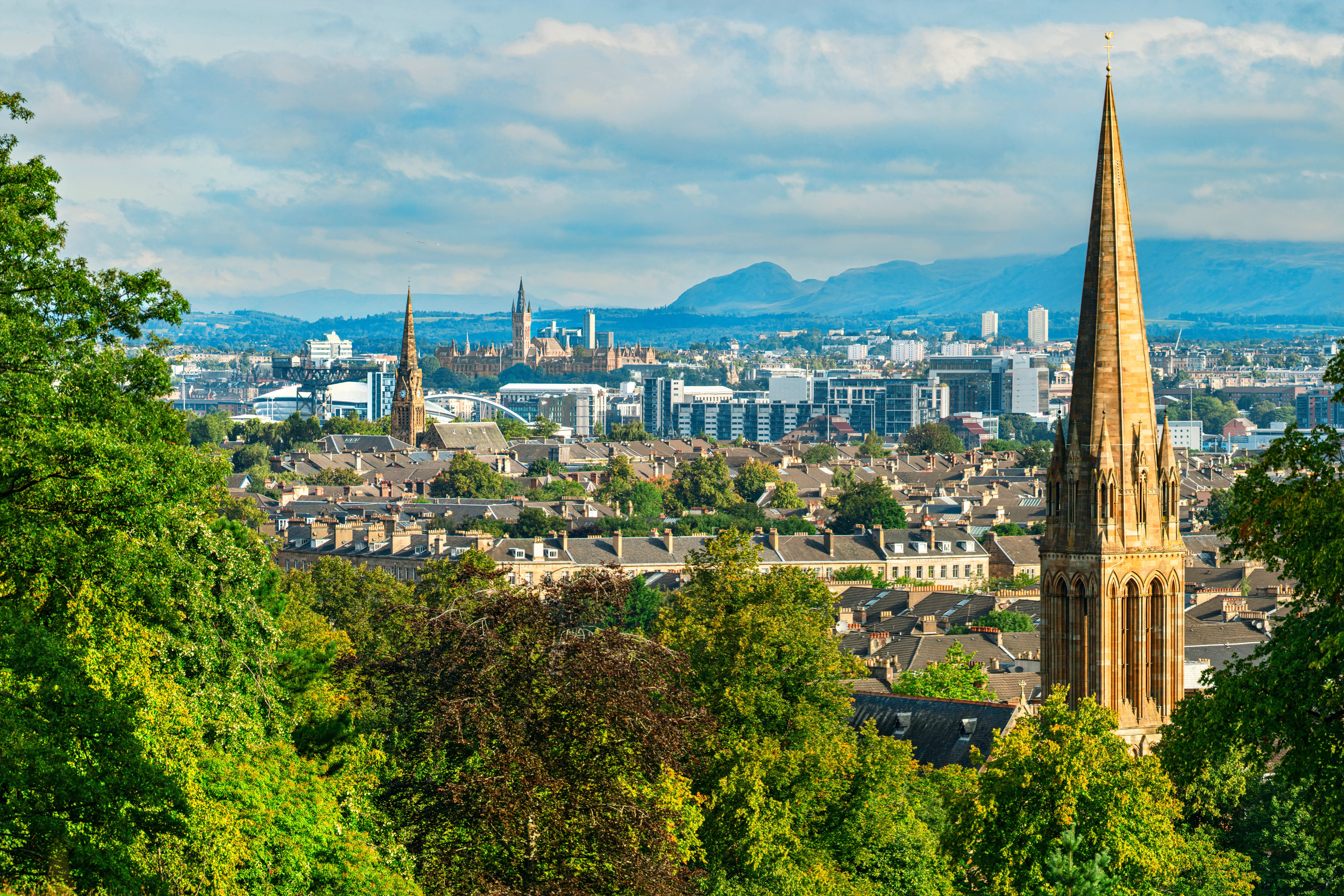 Blick vom Queens Park über Glasgow mit markanten Kirchturmspitzen und Hügeln im Hintergrund.