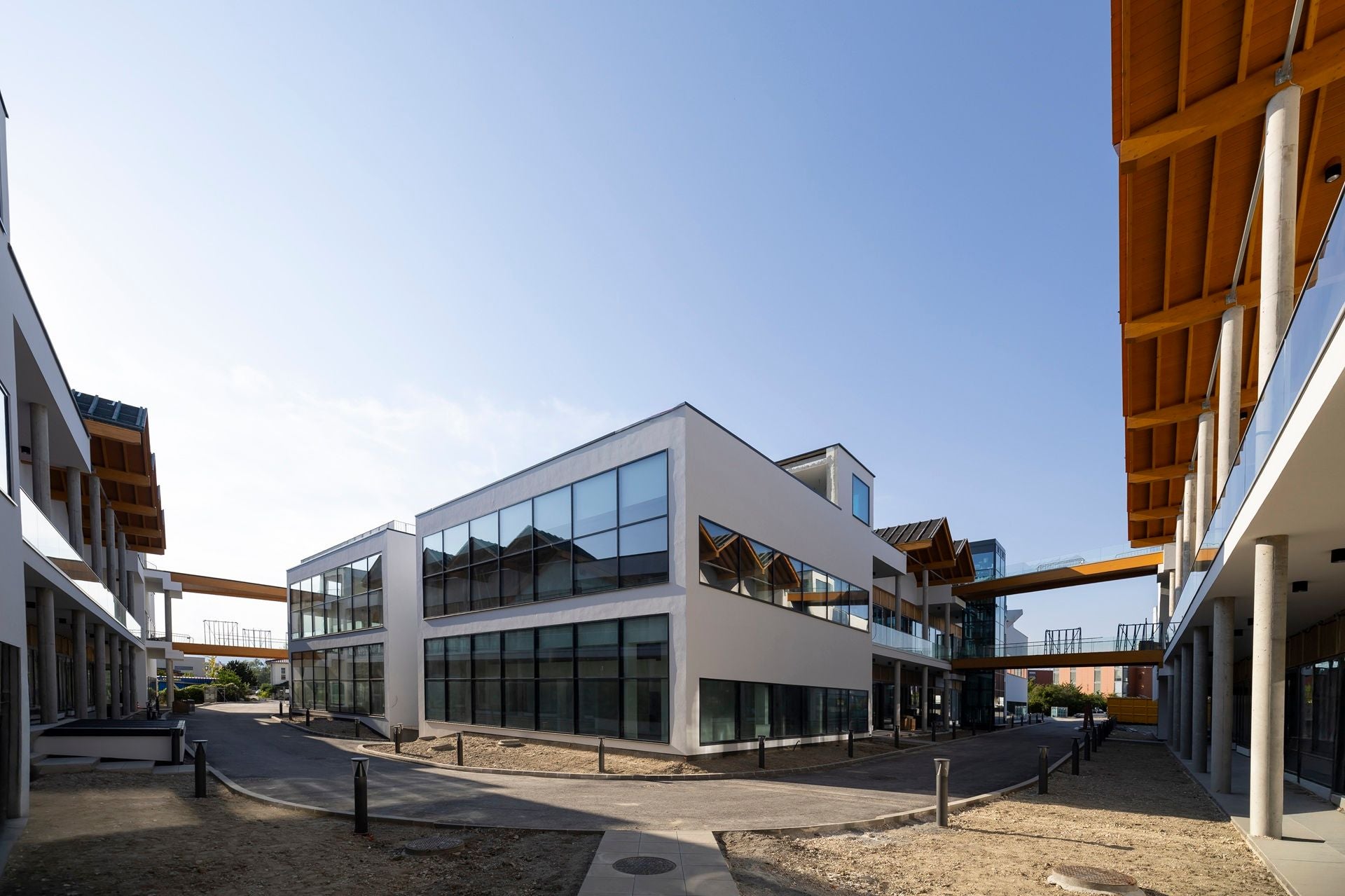 Moderne Bürogebäude mit großen Glasfenstern und Stegen zwischen den Häusern bei klarem Himmel.