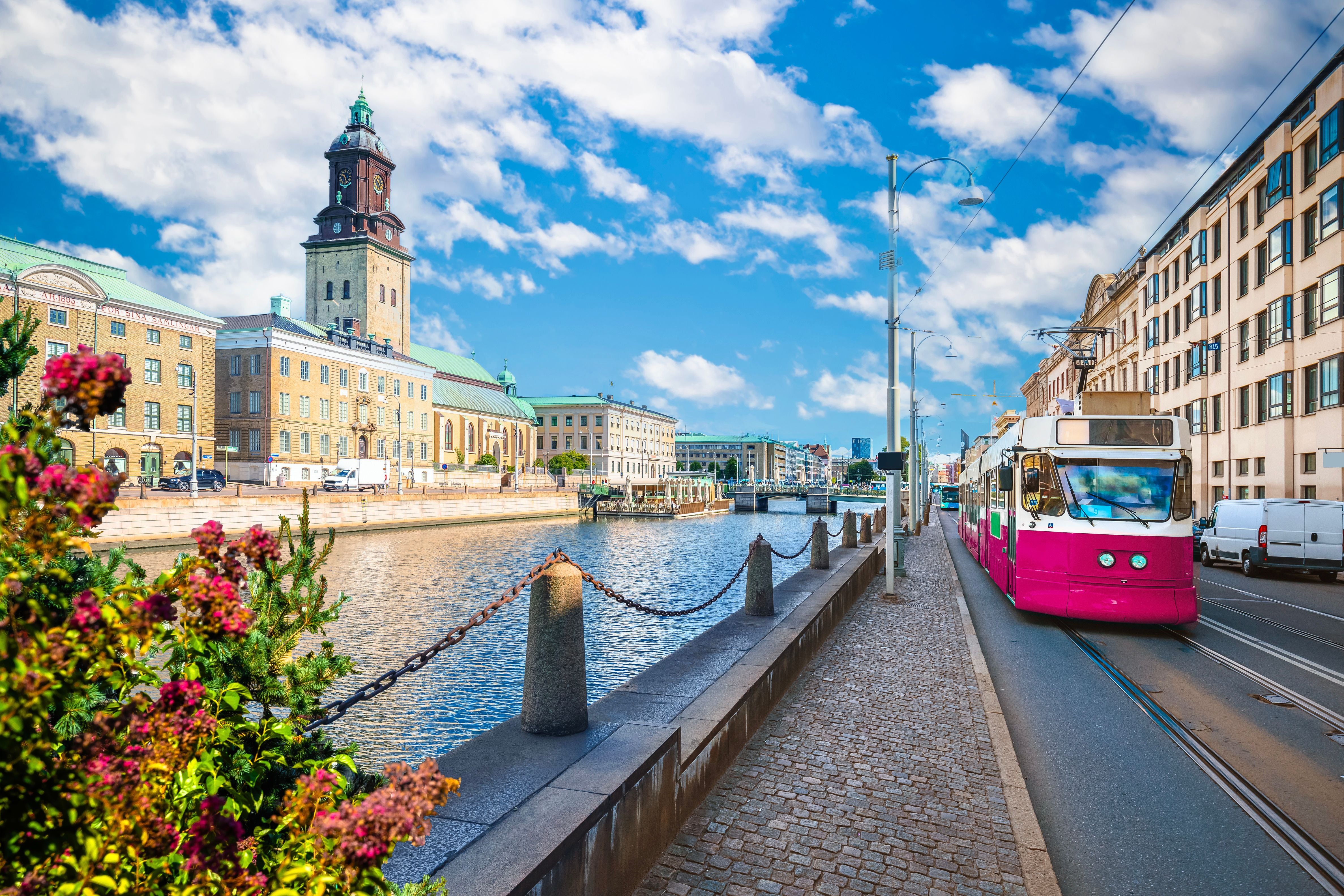 Straßenbahn fährt an einem Kanal mit historischen Gebäuden und Kirche in Göteborg entlang.