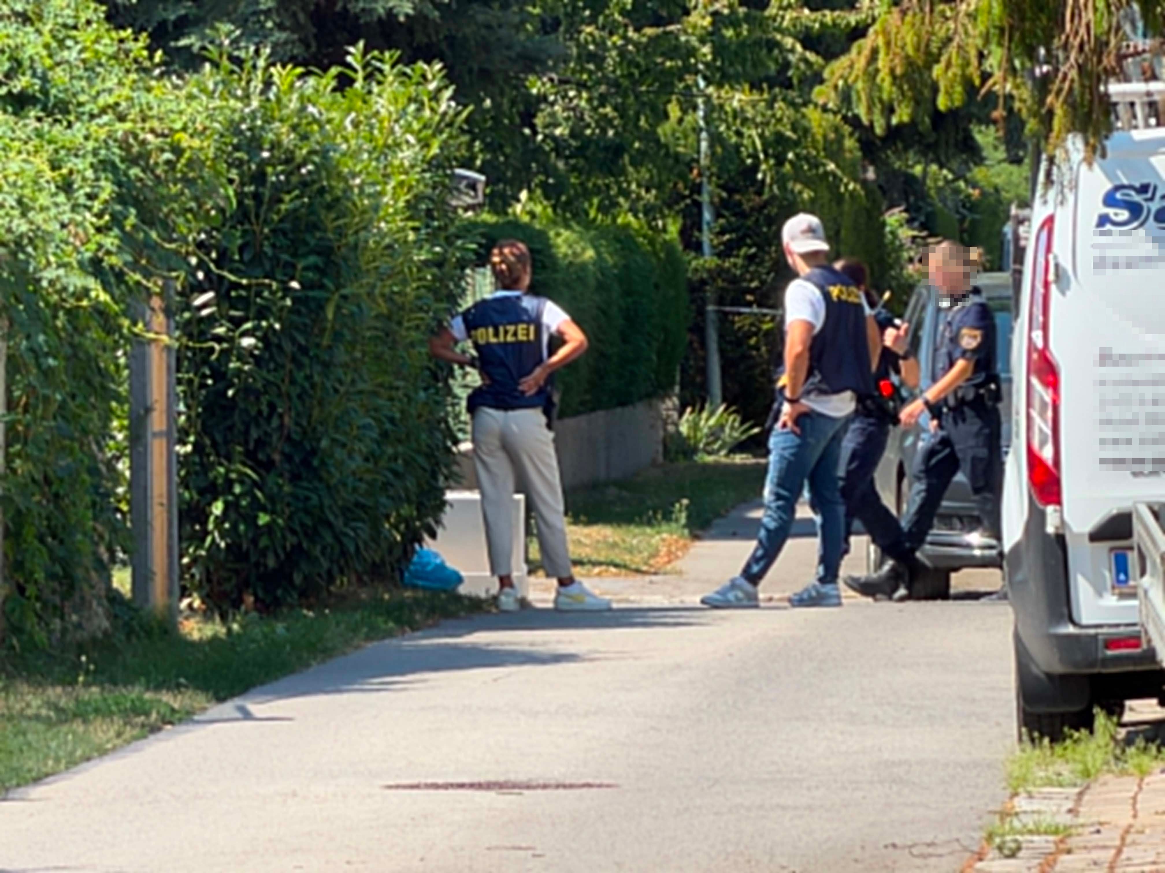 Vier Polizisten stehen auf einer abgesperrten Straße bei einem Einsatz in Langenzersdorf.