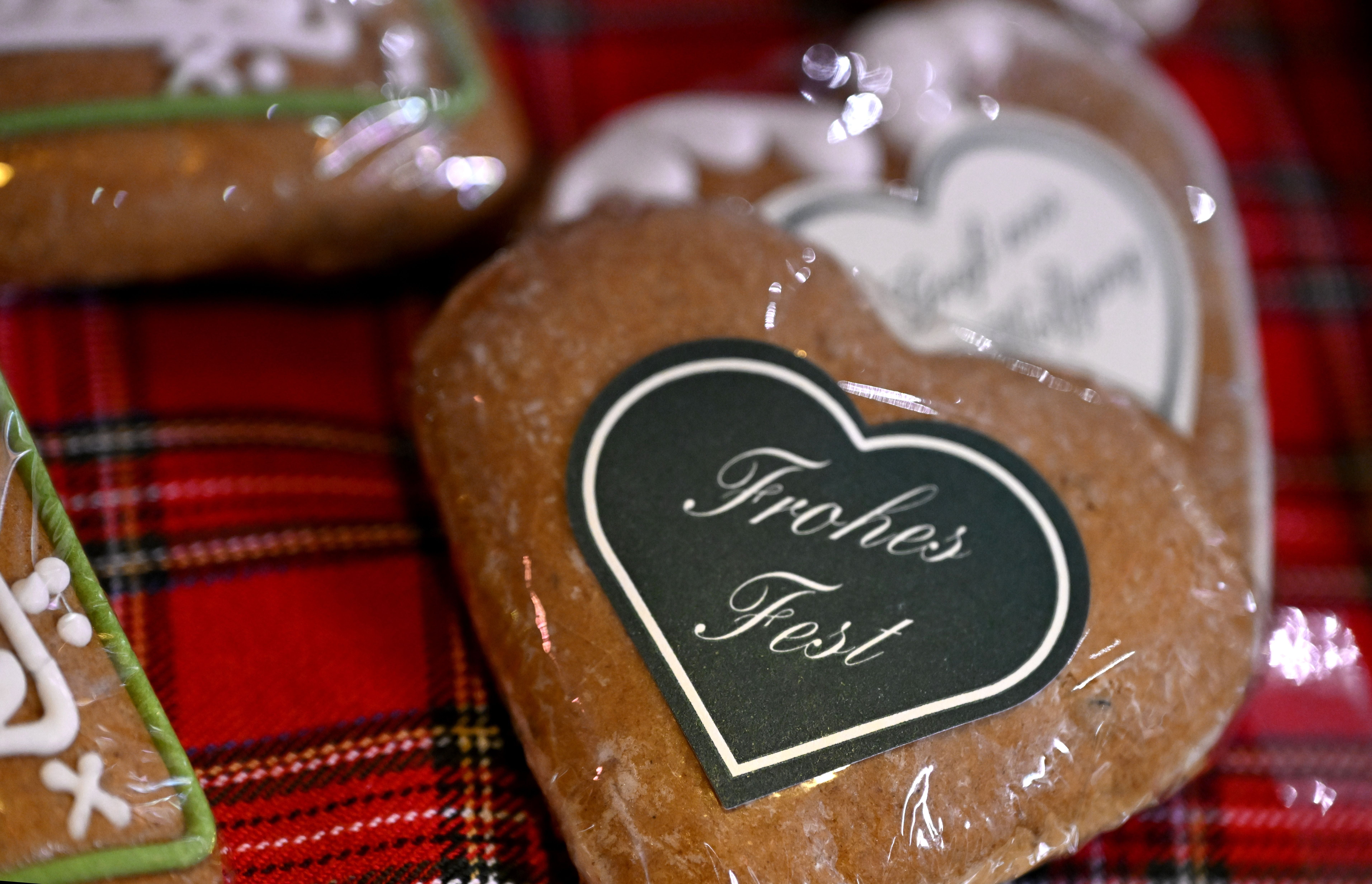 Herzförmiger Lebkuchen mit Schild "Frohes Fest" auf rotem karierten Tuch.