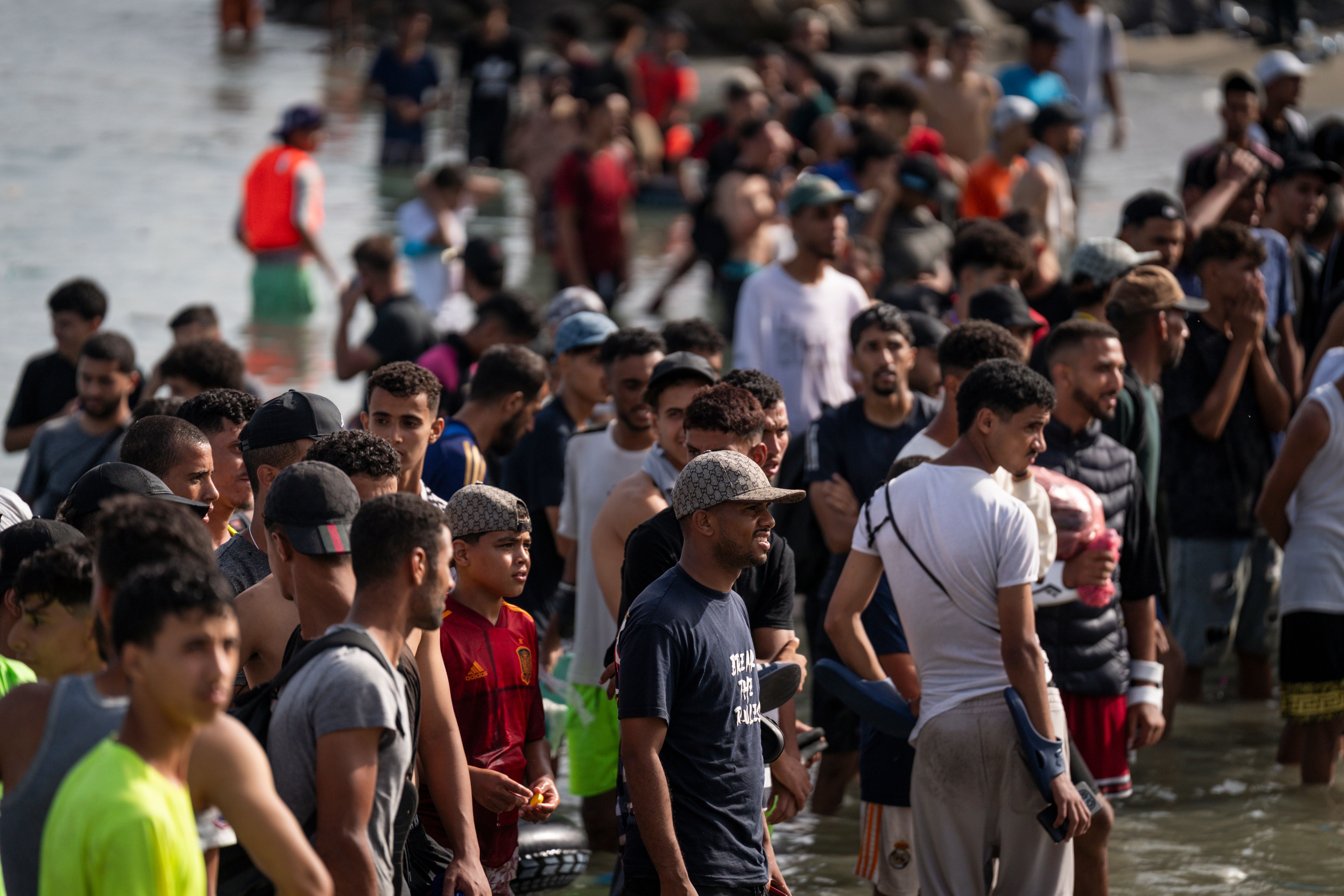 Viele Menschen stehen dicht gedrängt am Ufer eines Strandes im seichten Wasser.