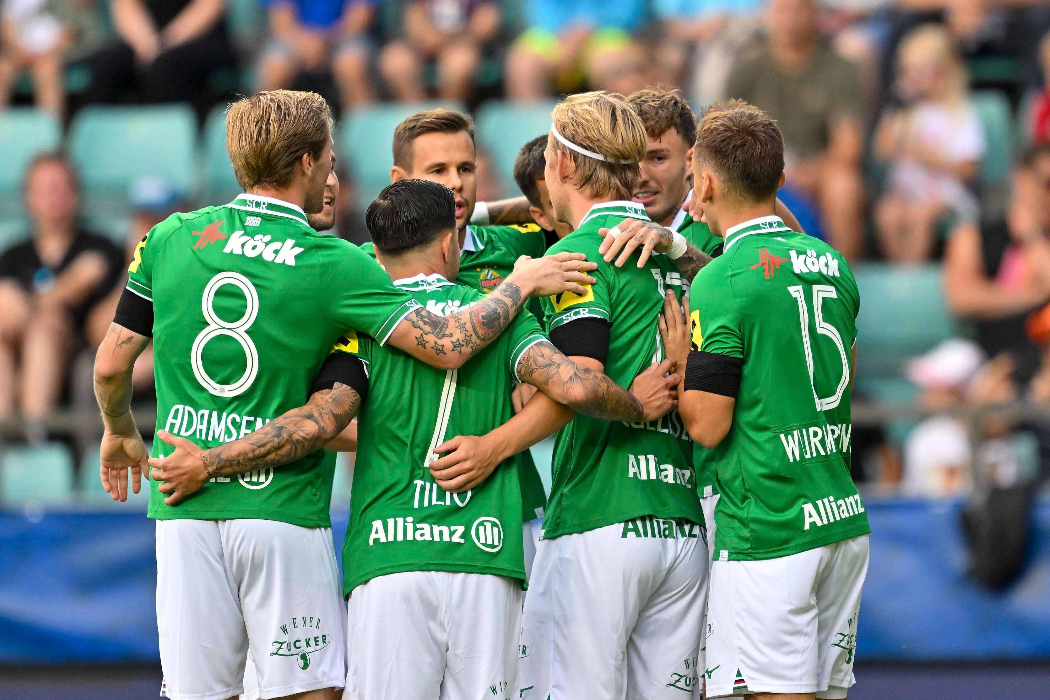Mehrere Fußballspieler im grünen Trikot feiern gemeinsam auf dem Spielfeld.