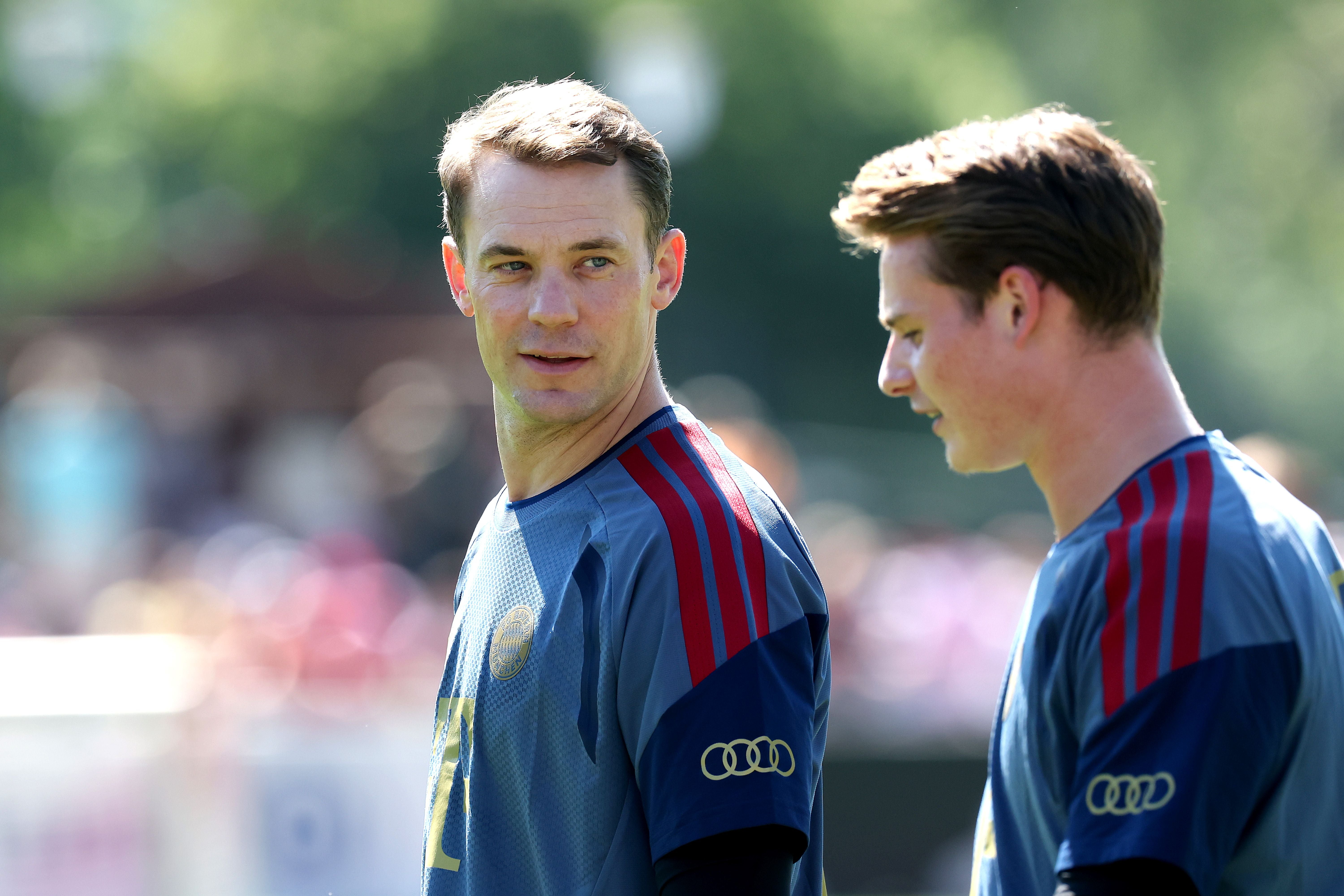 Zwei Fußballspieler im Trainingsoutfit unterhalten sich draußen beim FC Bayern Training.