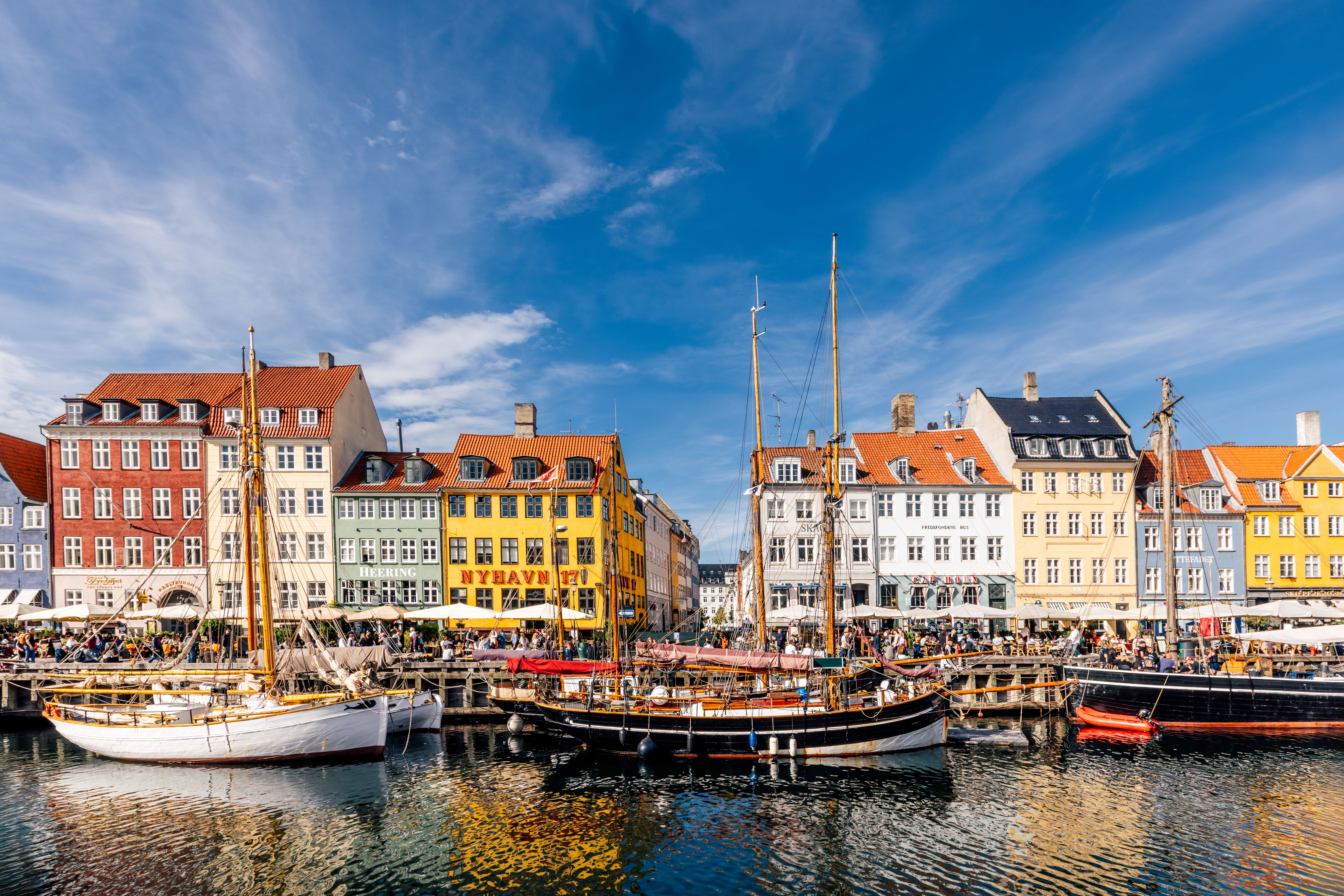 Bunte Häuser und Segelboote am Hafen von Nyhavn in Kopenhagen bei sonnigem Wetter.