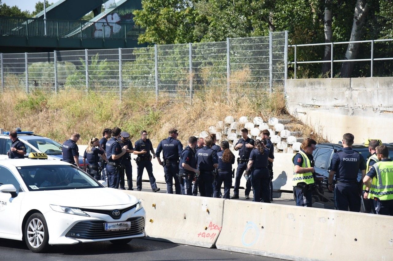 Viele Polizisten stehen auf einer Autobahn neben einem Taxi und mehreren Polizeifahrzeugen.