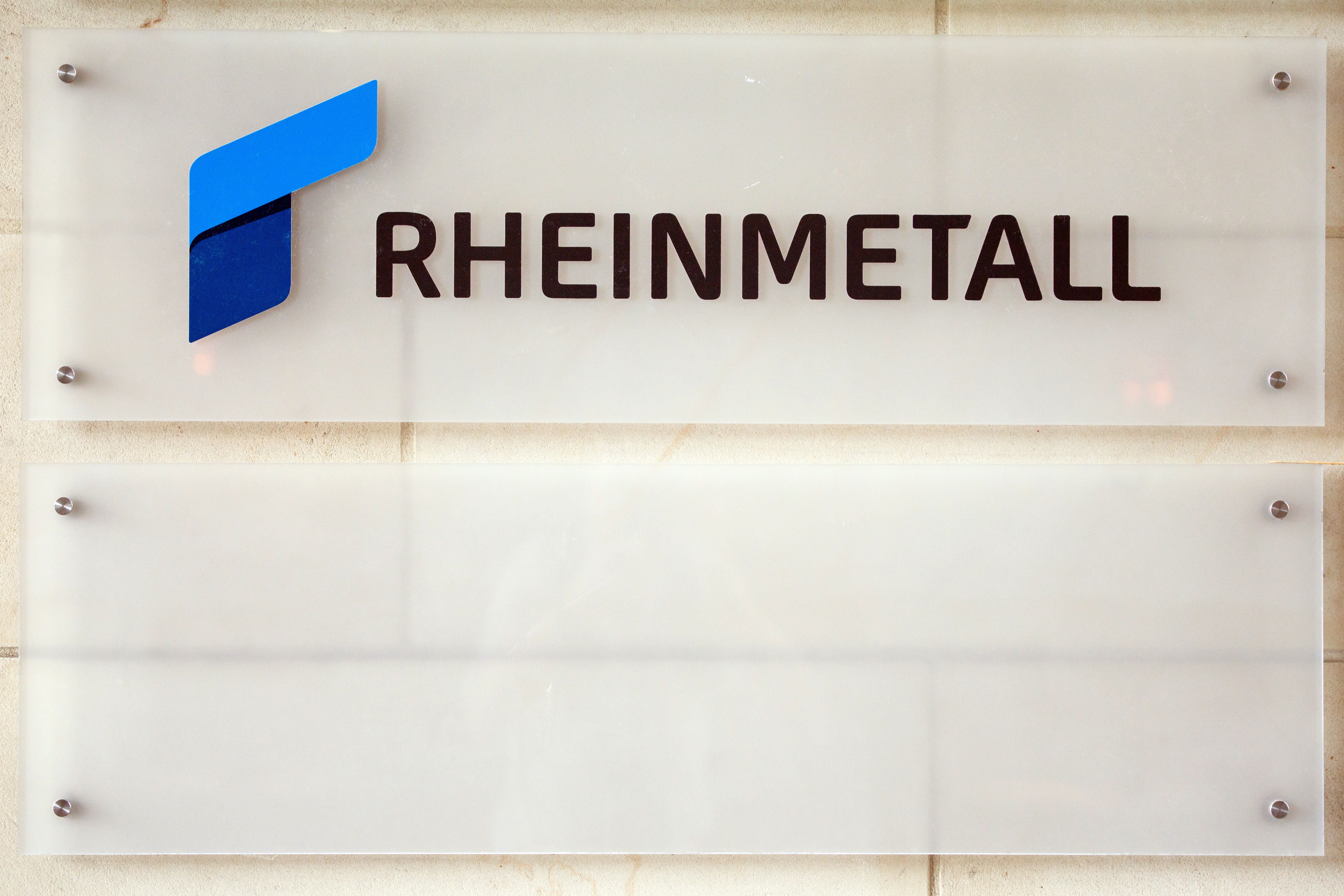 Rheinmetall-Logo und Schriftzug auf einer Glastafel an einer Wand.
