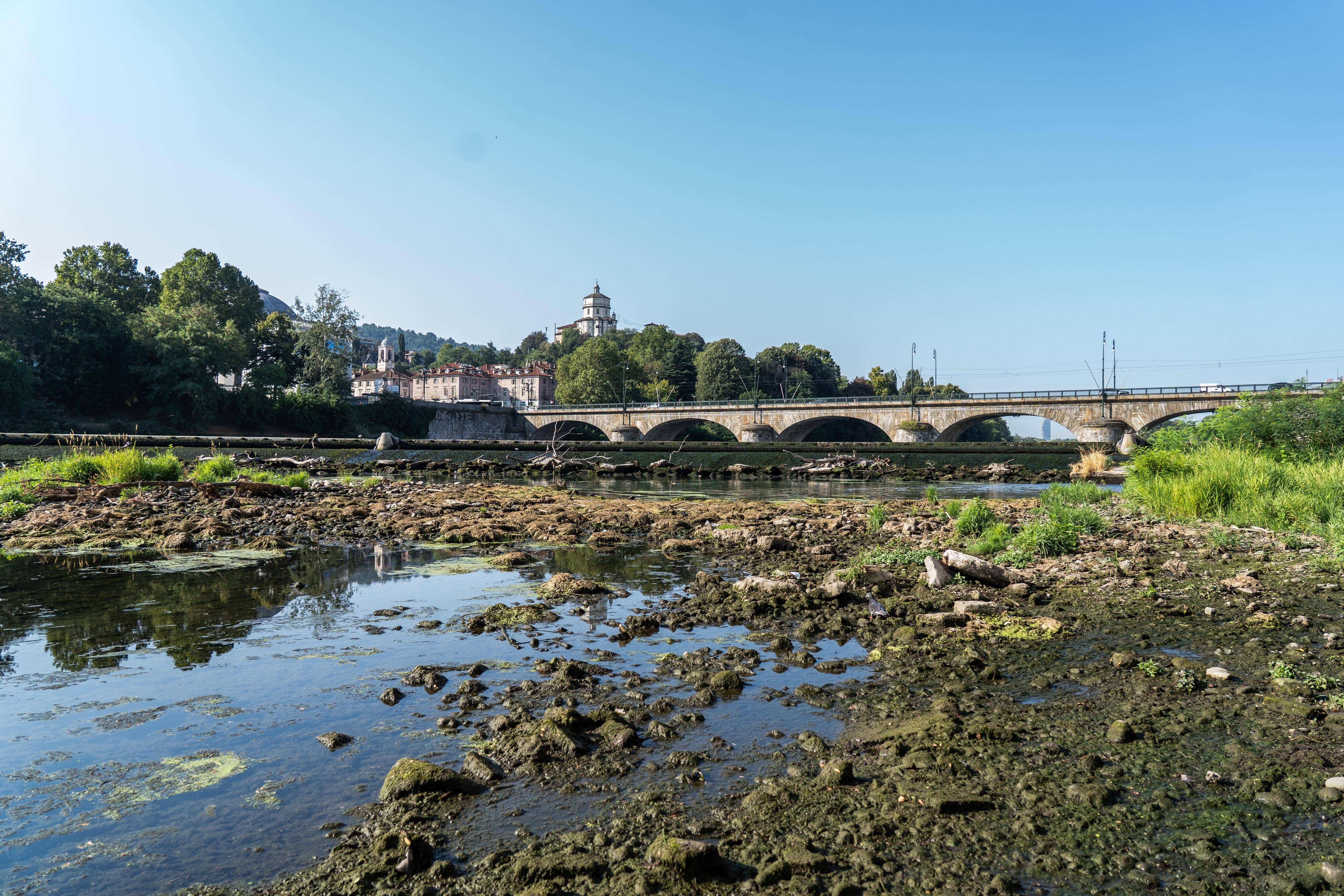 Ausgetrocknetes Flussbett des Po mit Brücke und Stadtansicht im Hintergrund in Turin.