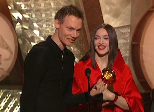 Ein Mann und eine Frau halten lachend einen Grammy Award auf einer Bühne.