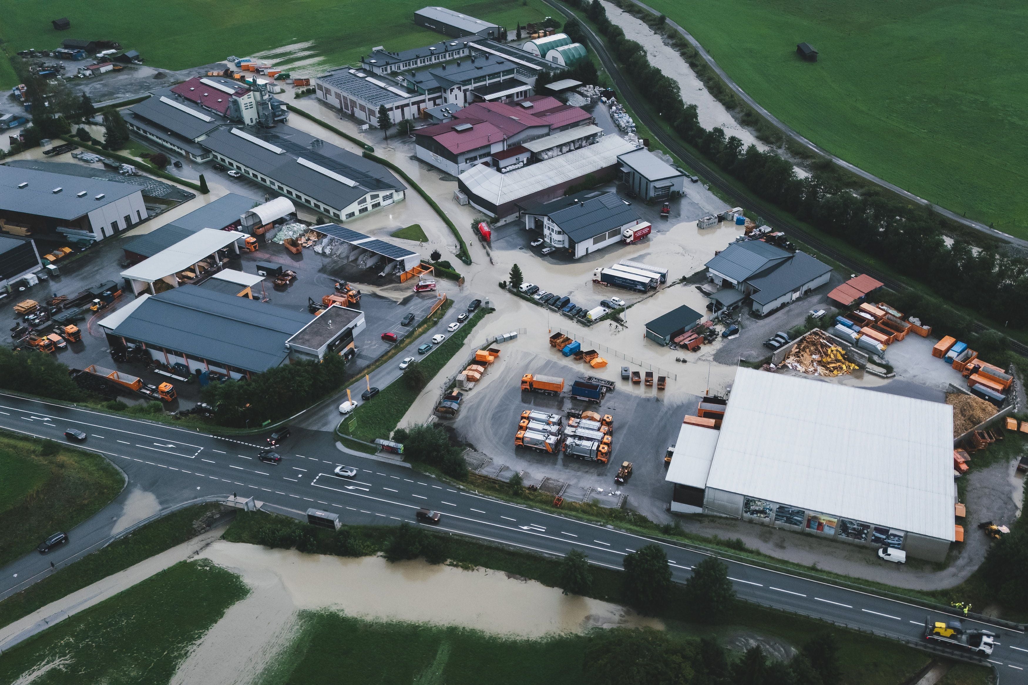 Luftaufnahme eines Industriegebiets in Uttendorf nach Überschwemmung durch einen übergetretenen Bach.