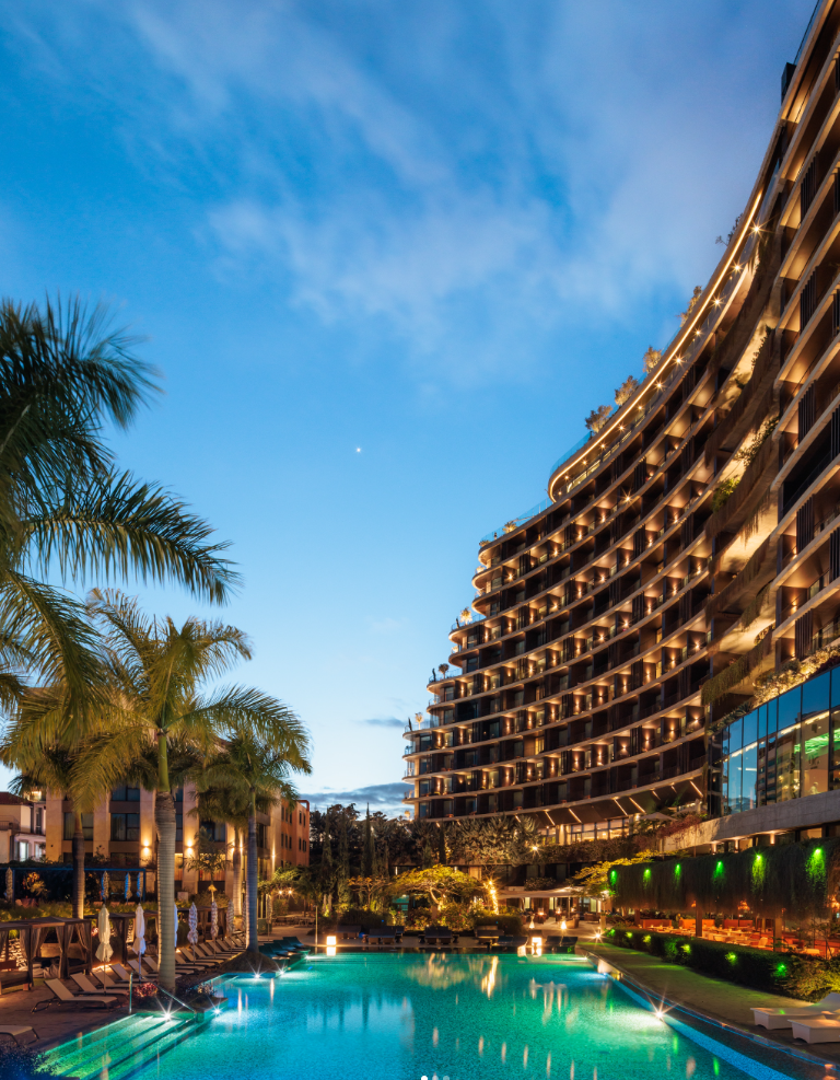 Abendaufnahme des beleuchteten Savoy Palace Hotels mit Pool und Palmen auf Madeira.