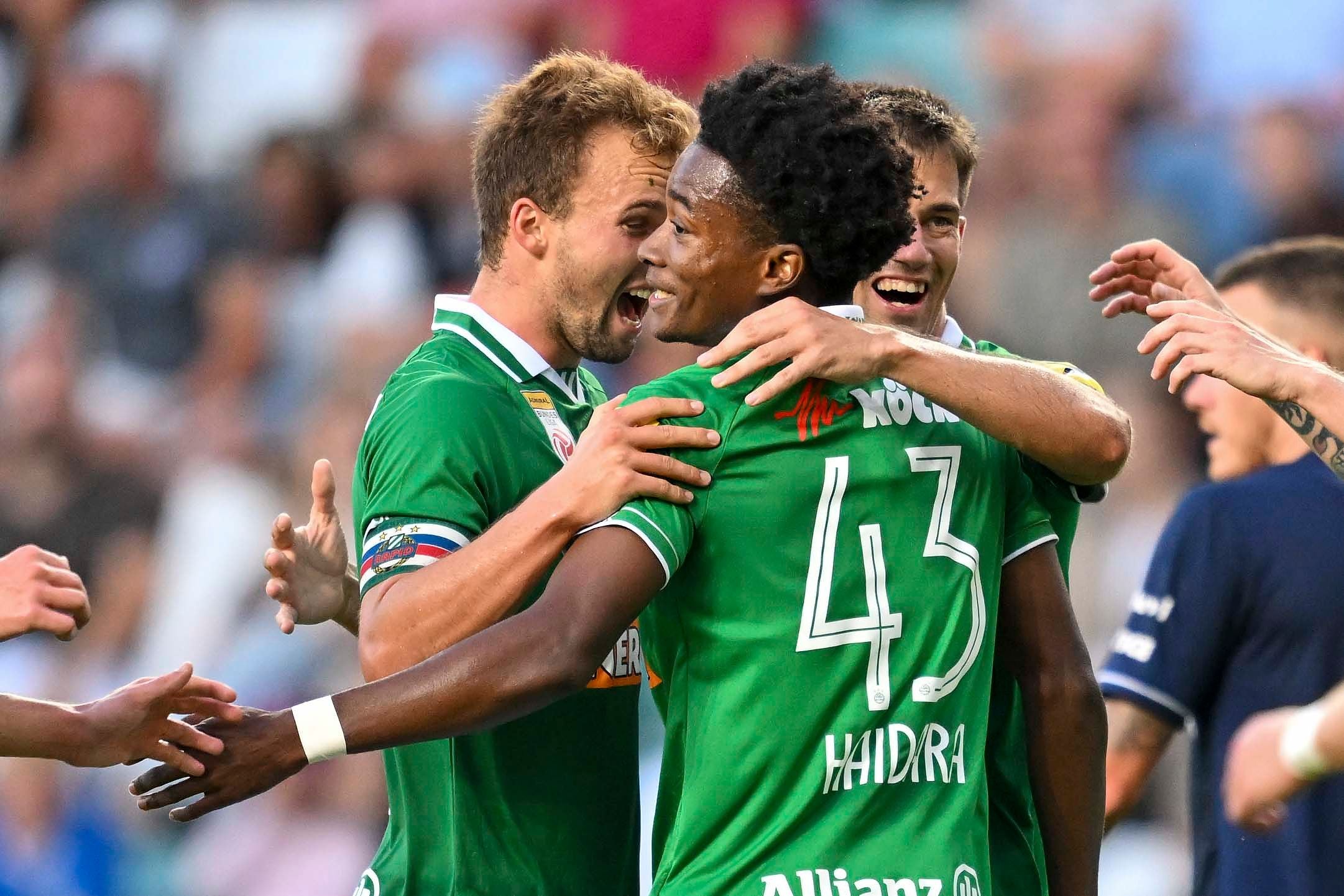Drei Rapid-Spieler jubeln im grünen Trikot über ein Tor, Haidara vorne in der Mitte.