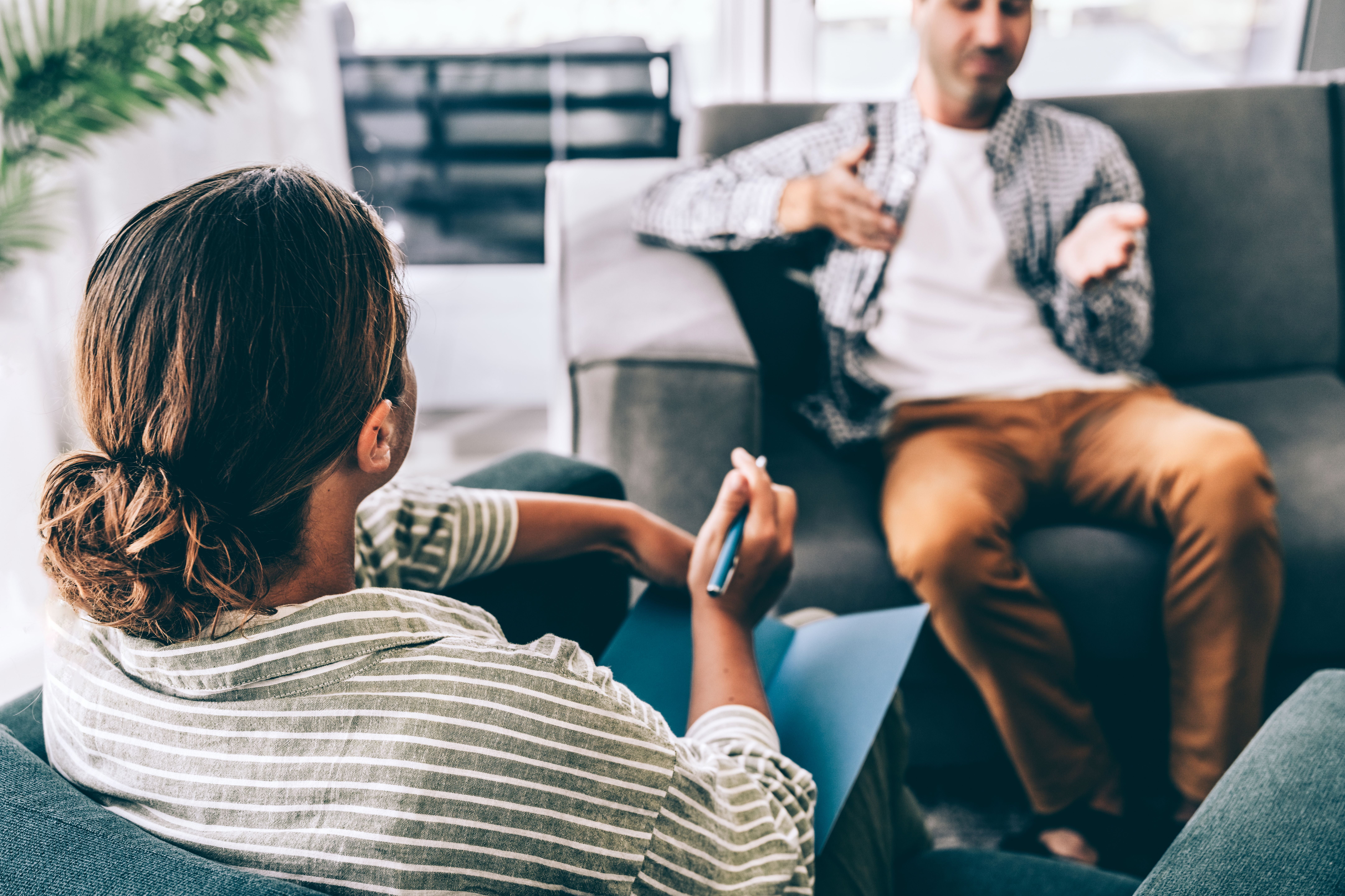 Zwei Personen sitzen sich in einem modernen Raum gegenüber, eine Gesprächstherapie findet statt.