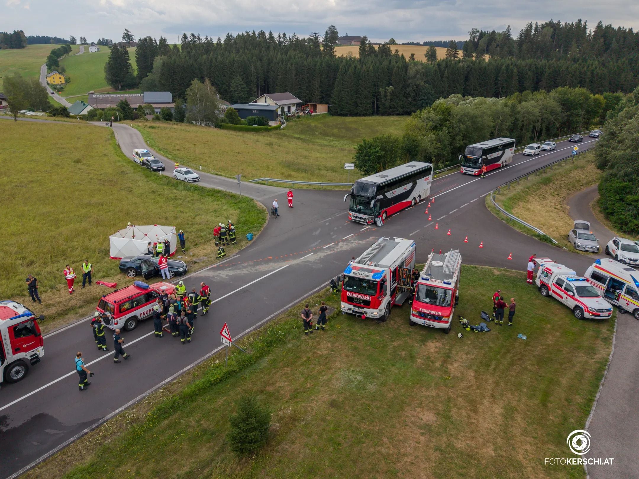 Unfallstelle mit Einsatzfahrzeugen, Feuerwehr, Rettungskräften und zwei Reisebussen an einer Kreuzung.