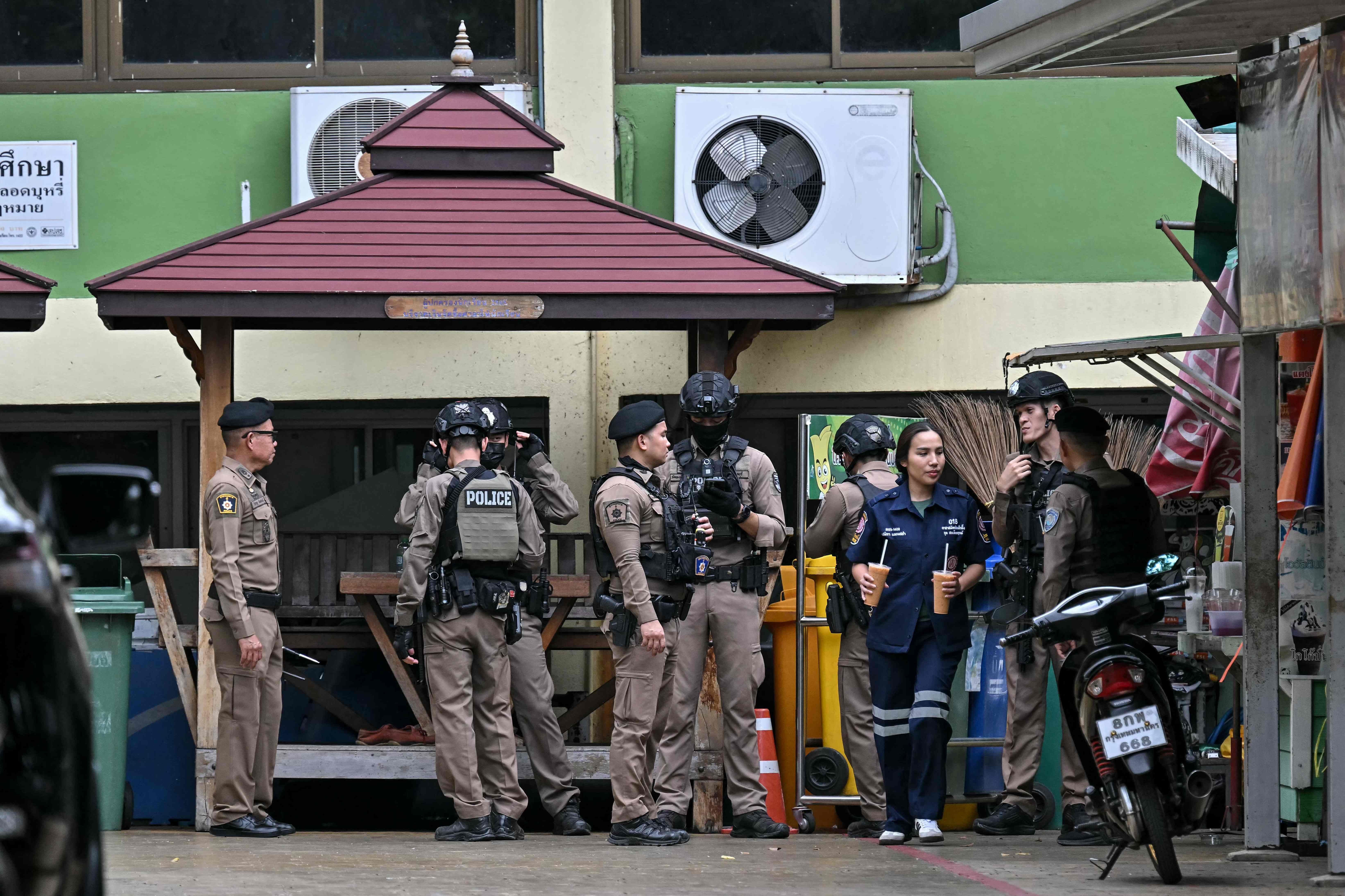 Mehrere Polizisten stehen nach einer Schießerei vor einem Gebäude in Thailand zusammen.