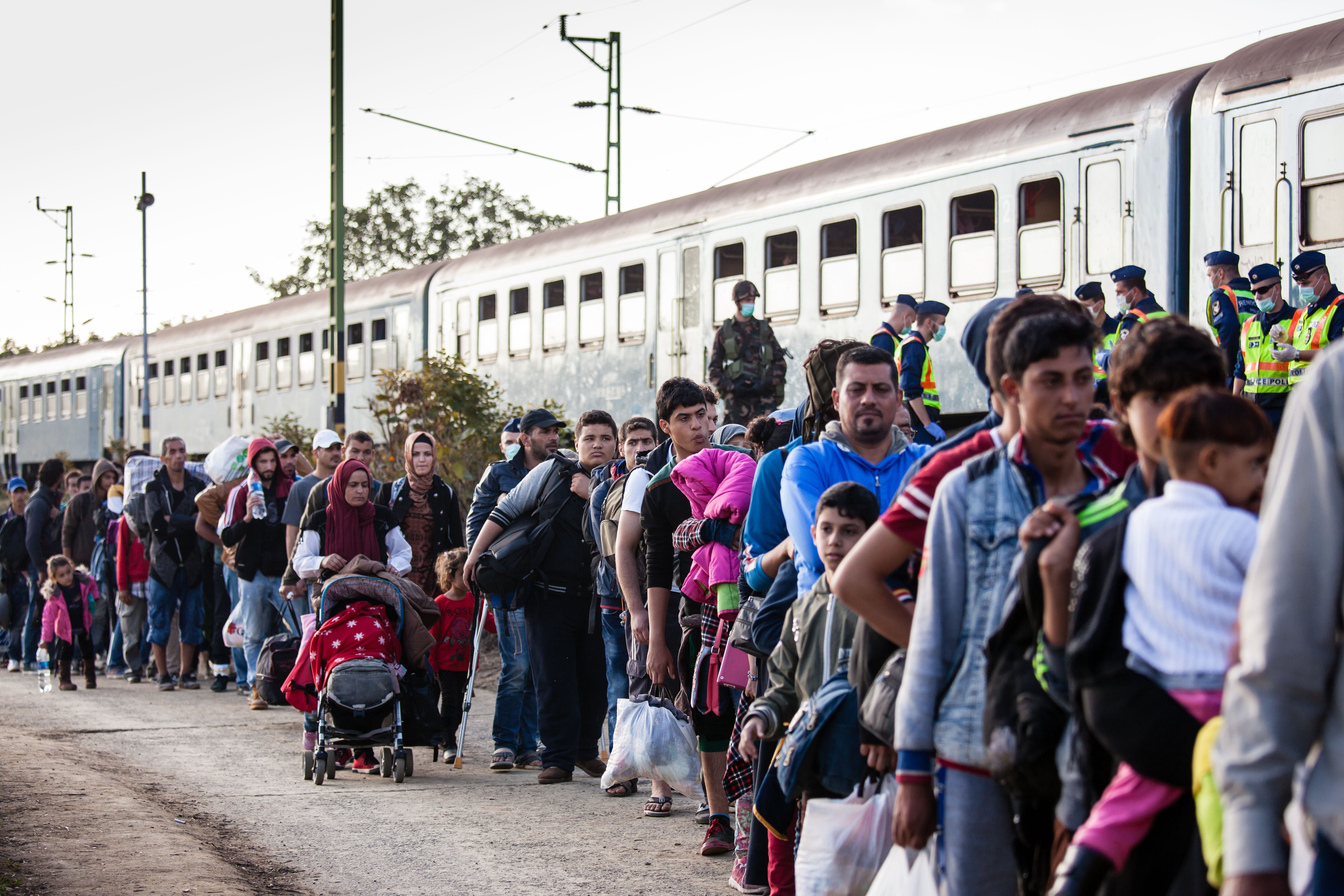 Flüchtlinge stehen an einem Bahnhof in Zakany, Ungarn, vor einem Zug in einer langen Schlange.