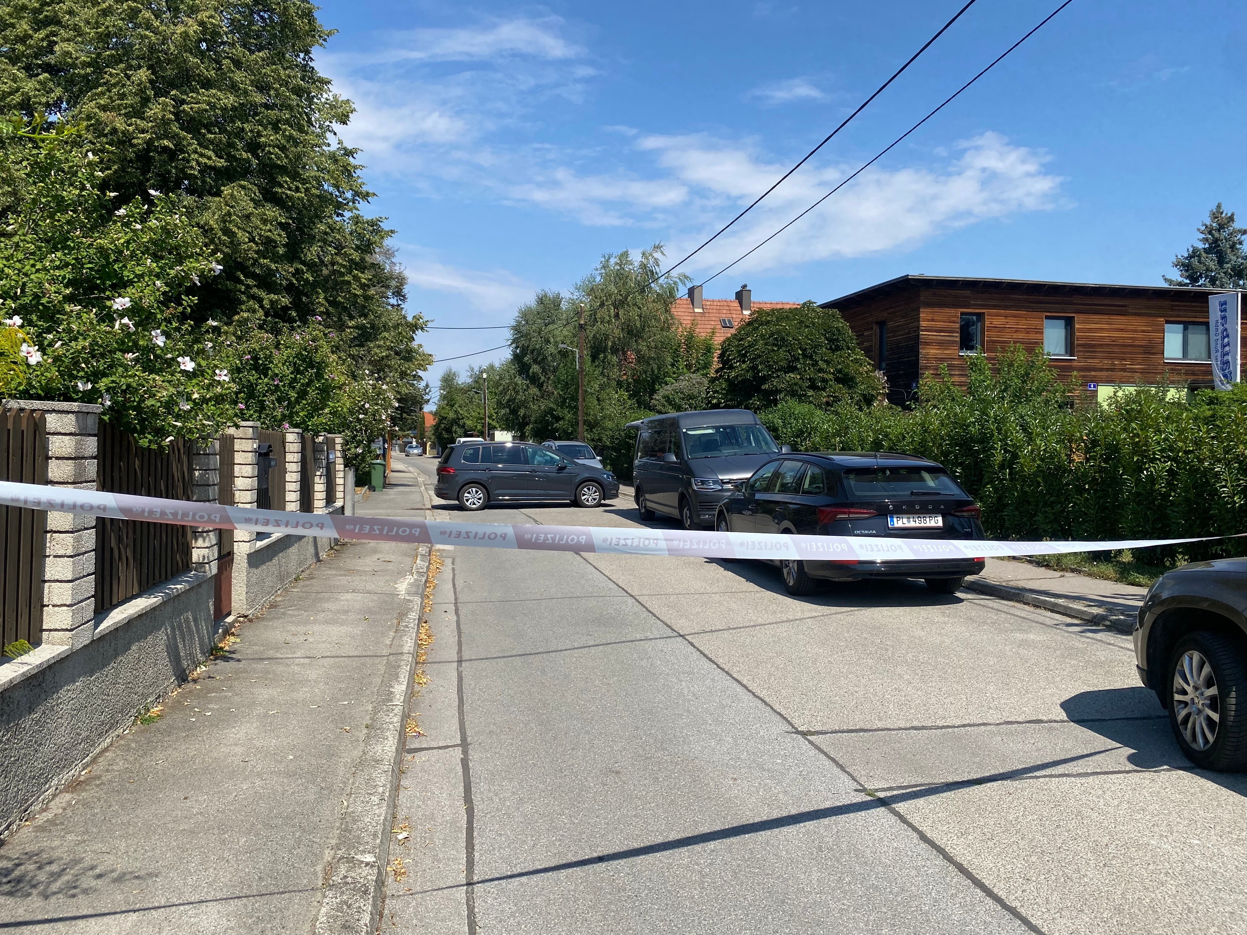 Eine mit "Polizei"-Band abgesperrte Straße in einem Wohnviertel bei sonnigem Wetter.