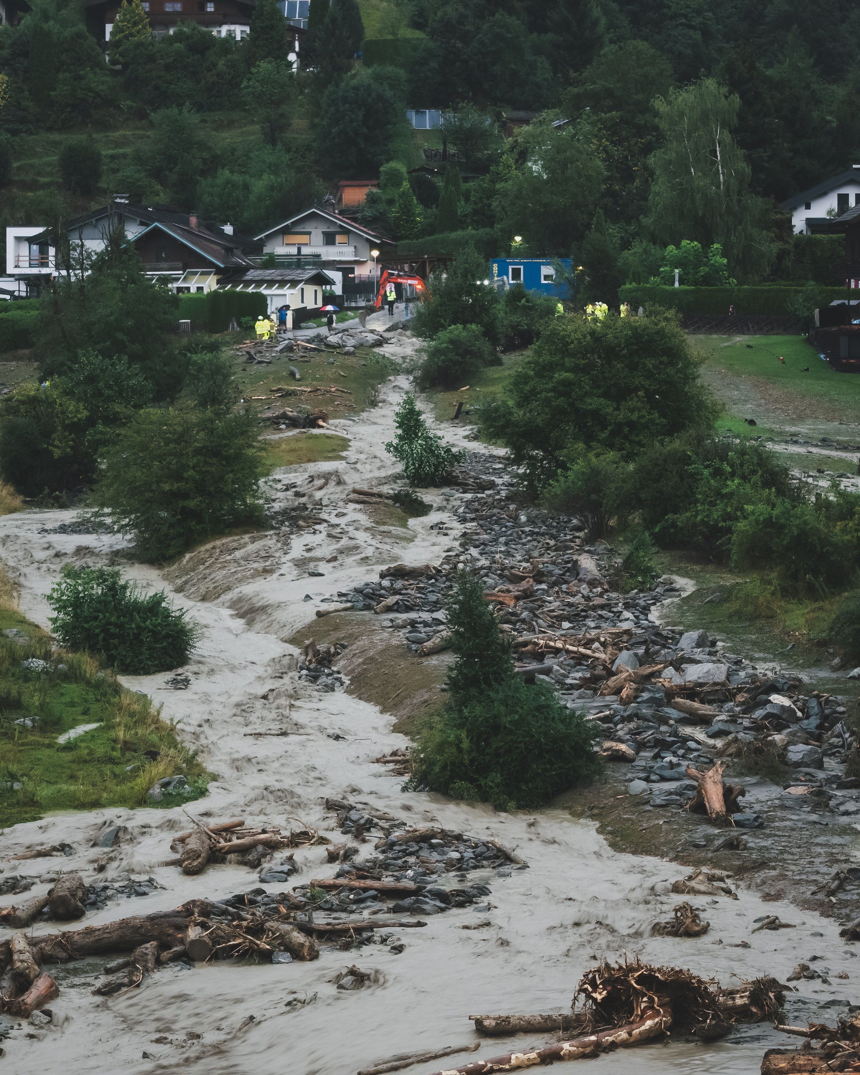 Stark angeschwollener Bach mit Treibholz und Geröll nach Überschwemmung in Uttendorf, Österreich.