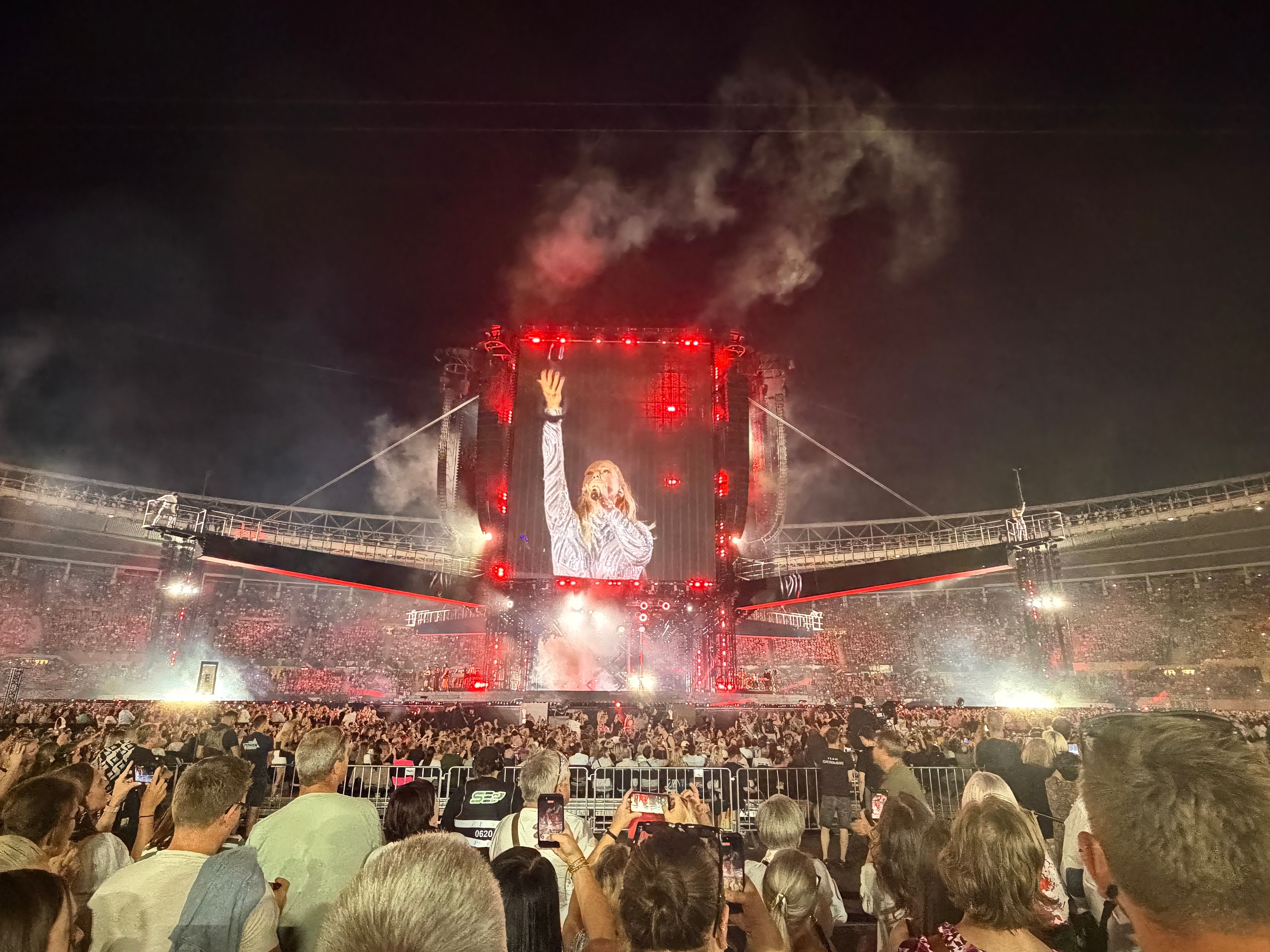 Helene Fischer bei einem Konzert auf einer großen Bühne mit rotem Licht und vielen Zuschauern.