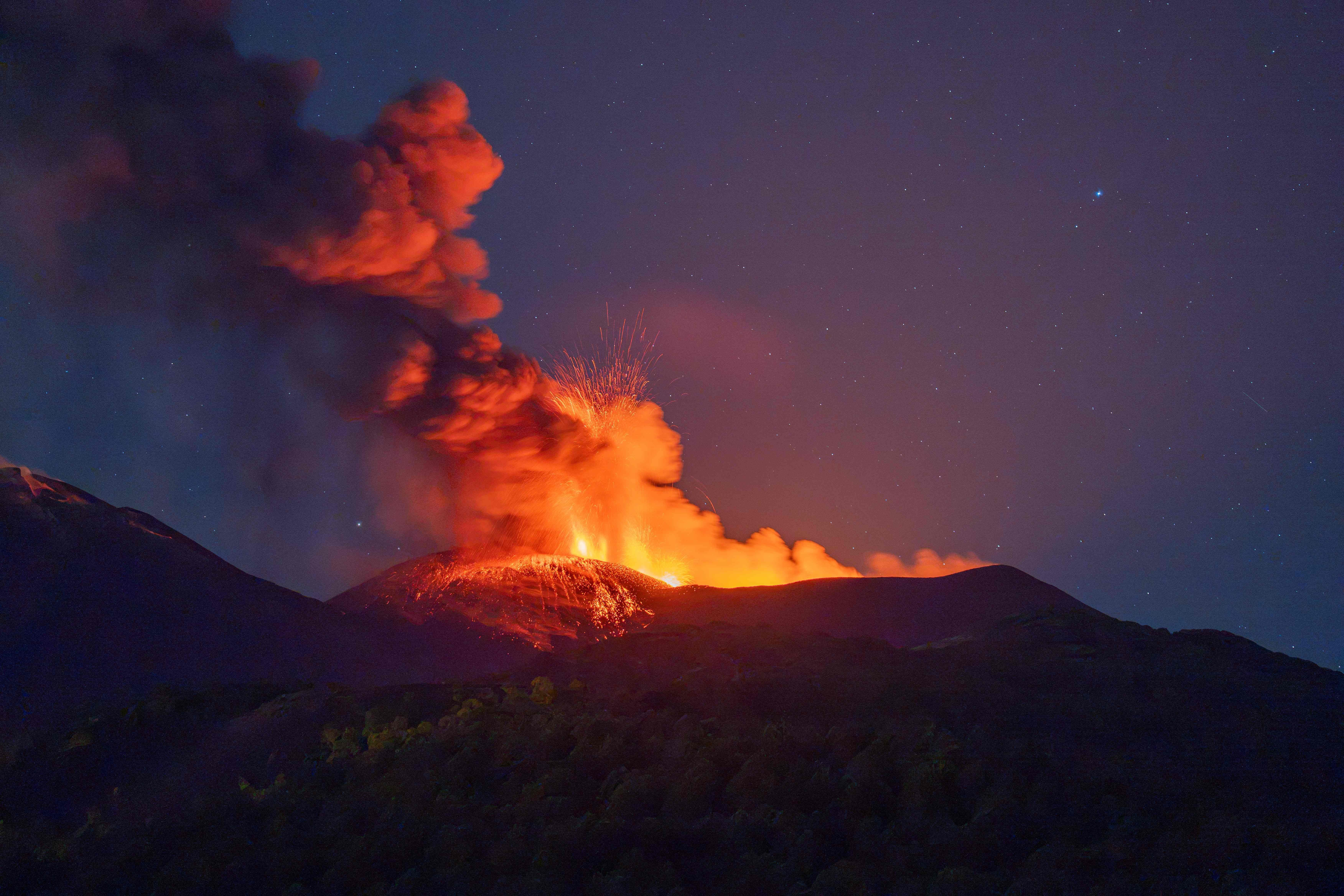 Der Vulkan Ätna stößt nachts Lava und dichte Rauchwolken aus.