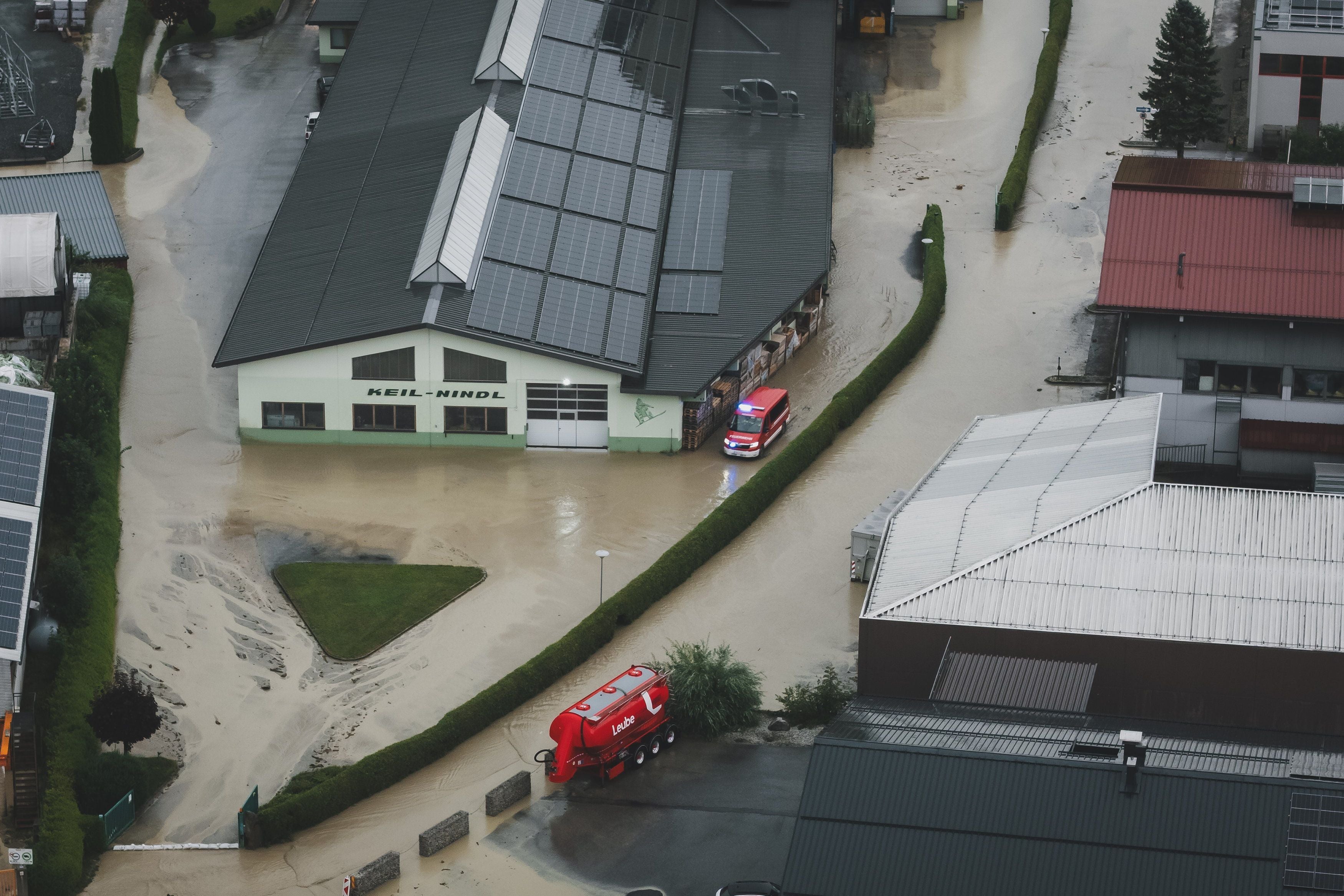 Luftaufnahme eines Industriegebiets in Uttendorf nach Überschwemmung mit Feuerwehrfahrzeugen.