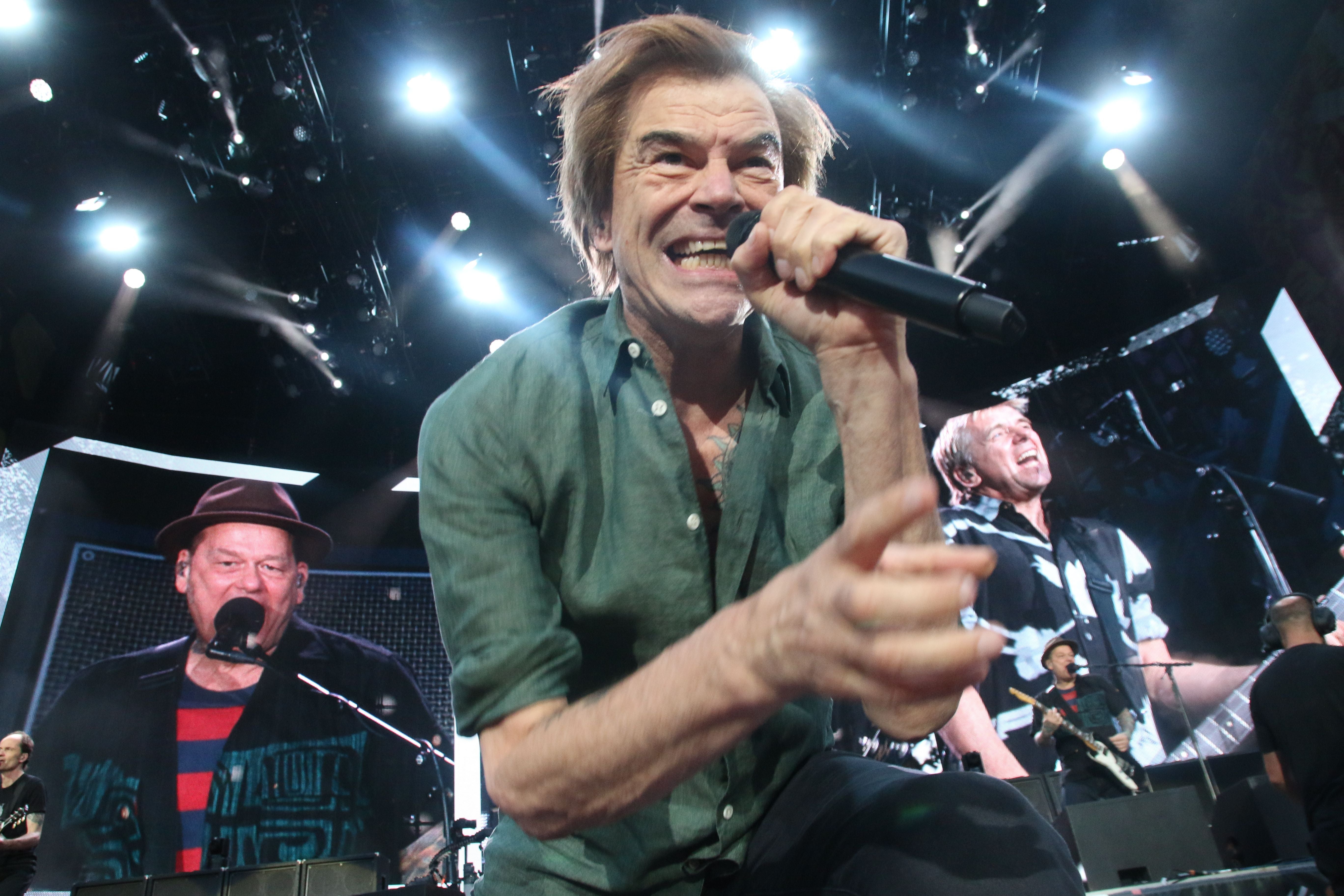 Ein Sänger der Band Die Toten Hosen performt energiegeladen auf einer großen Konzertbühne.