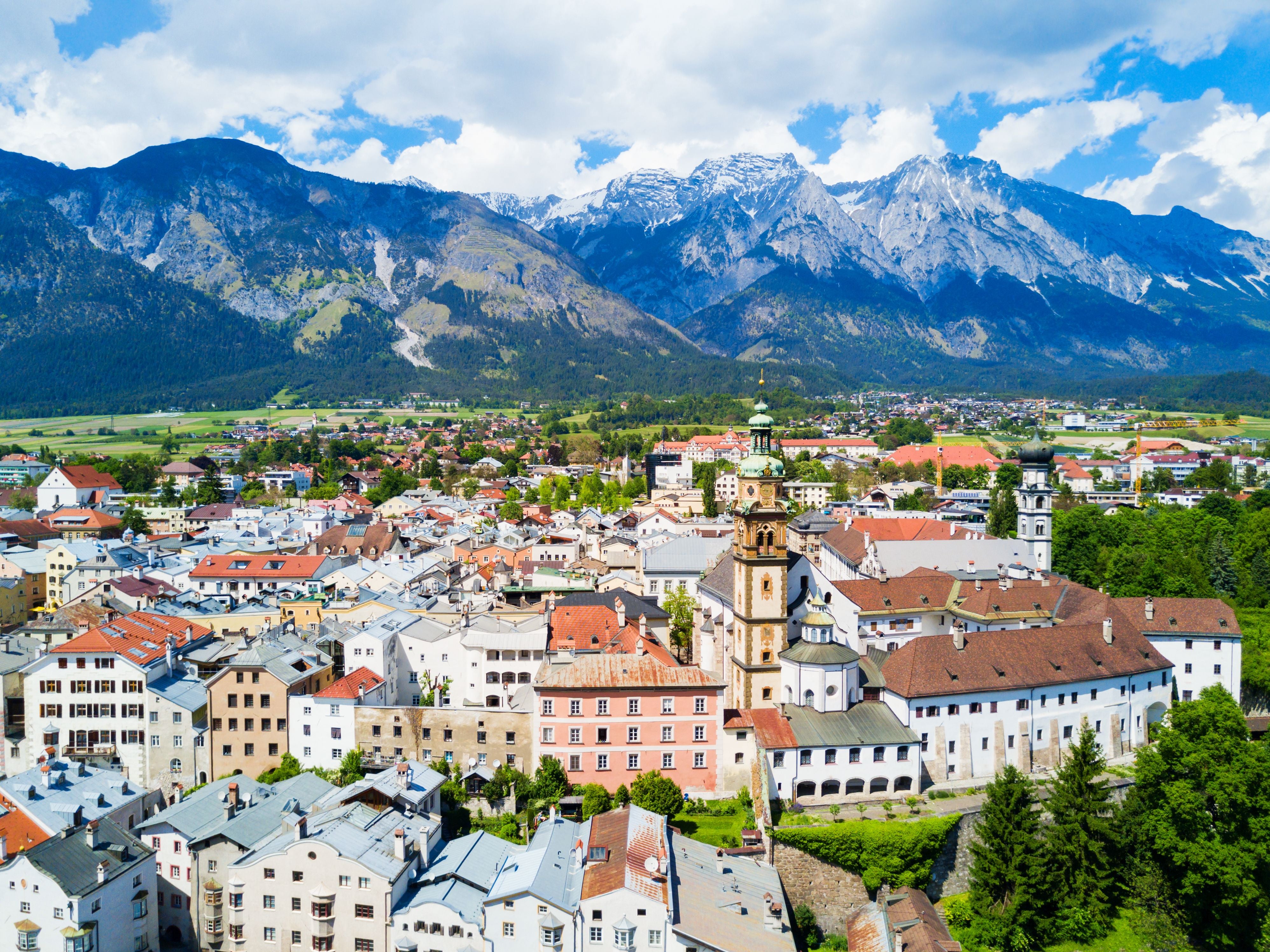 Panorama von Hall in Tirol mit der Stiftskirche Herz-Jesu-Basilika und Alpen im Hintergrund.