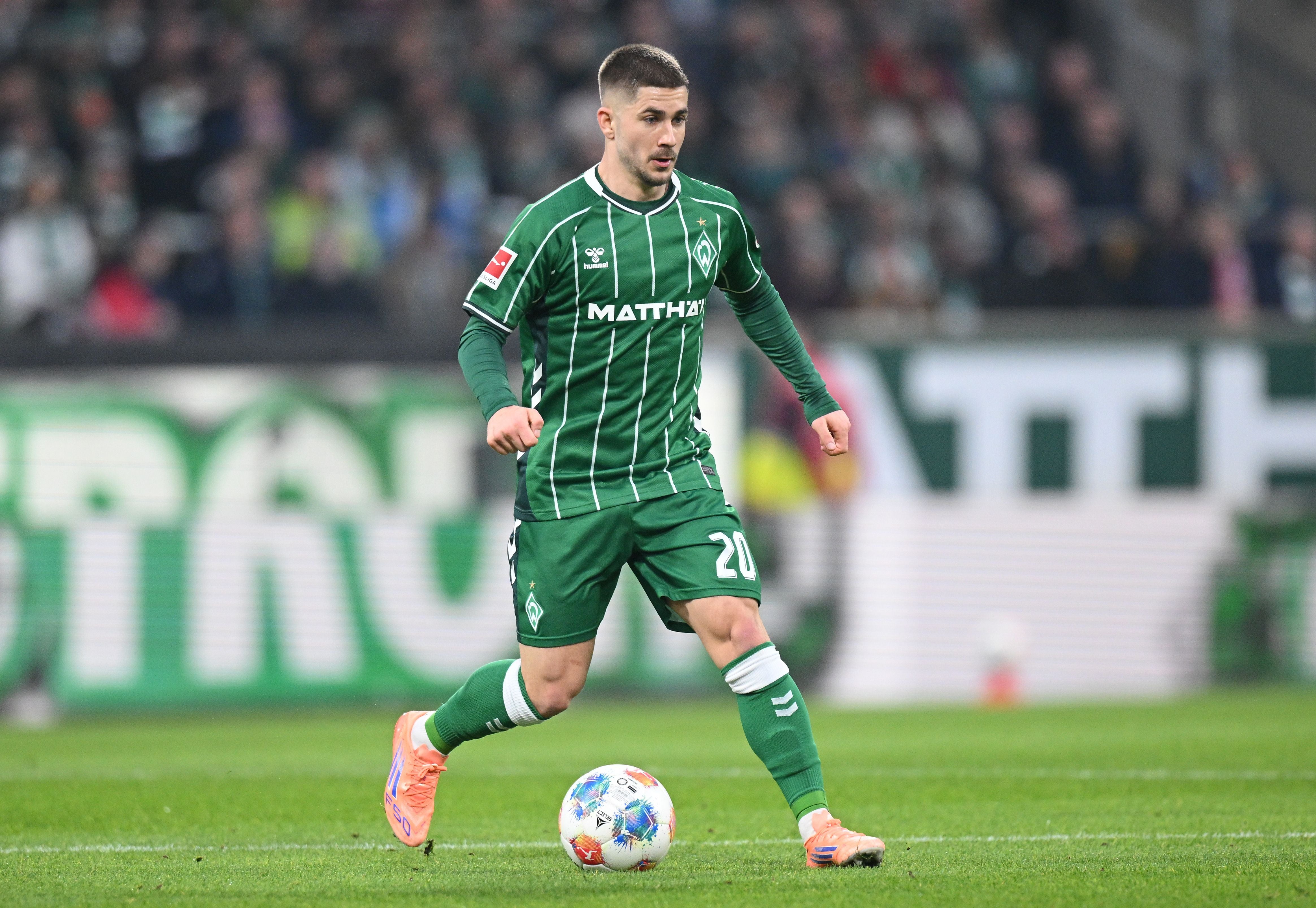 Ein Fußballspieler von Werder Bremen läuft mit dem Ball auf dem Spielfeld.