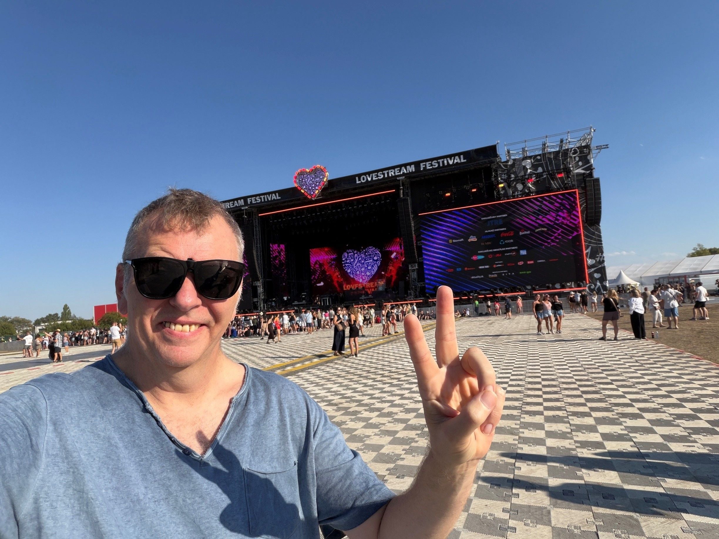 Mann mit Sonnenbrille zeigt Friedenszeichen vor einer Bühne beim Lovestream Festival.