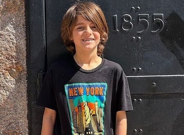 Junge mit schwarzem "New York"-T-Shirt steht vor einer schwarzen Tür mit der Zahl 1855.