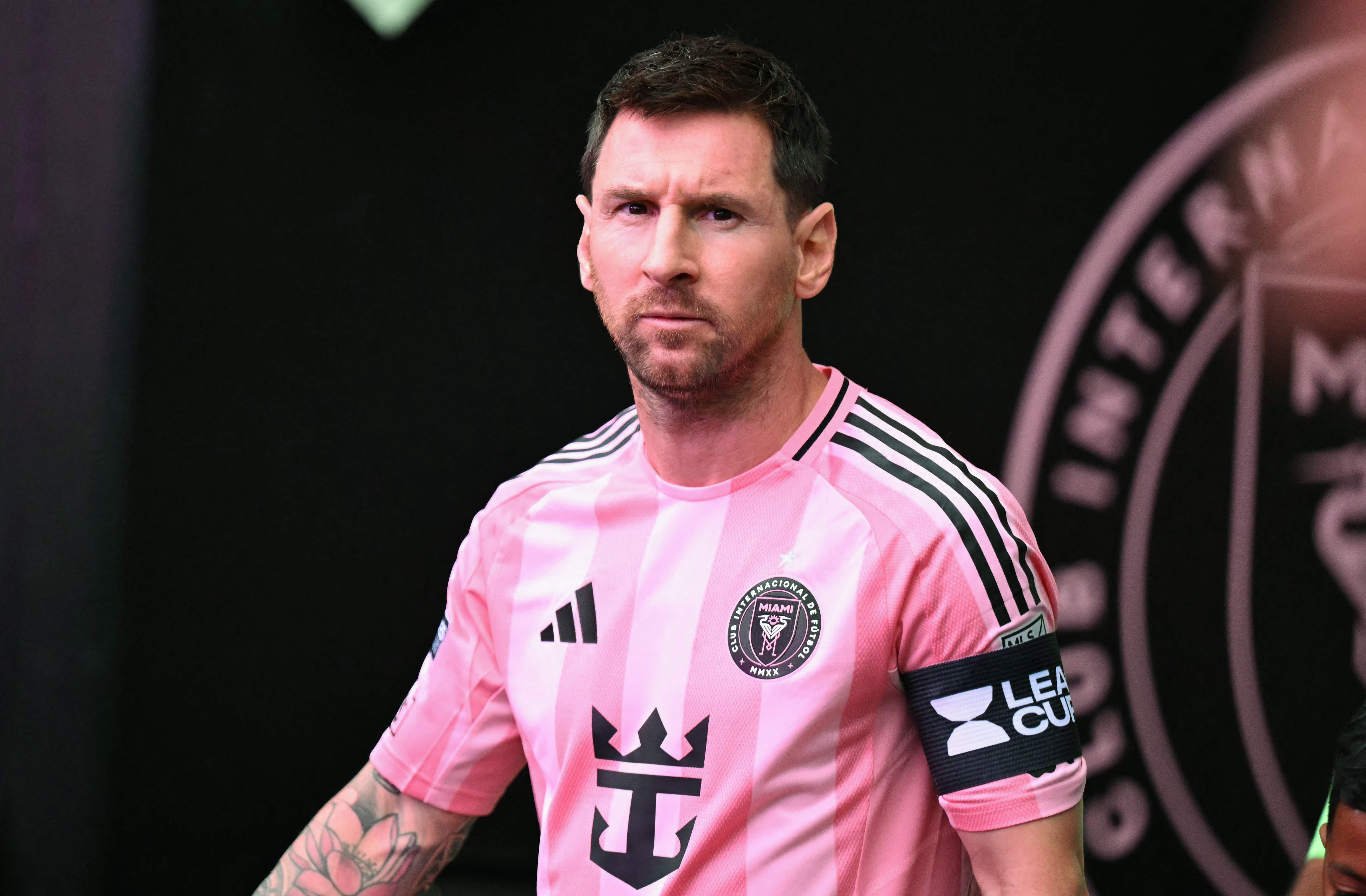 Ein Fußballspieler im pinken Inter-Miami-Trikot läuft mit ernster Miene auf das Spielfeld.