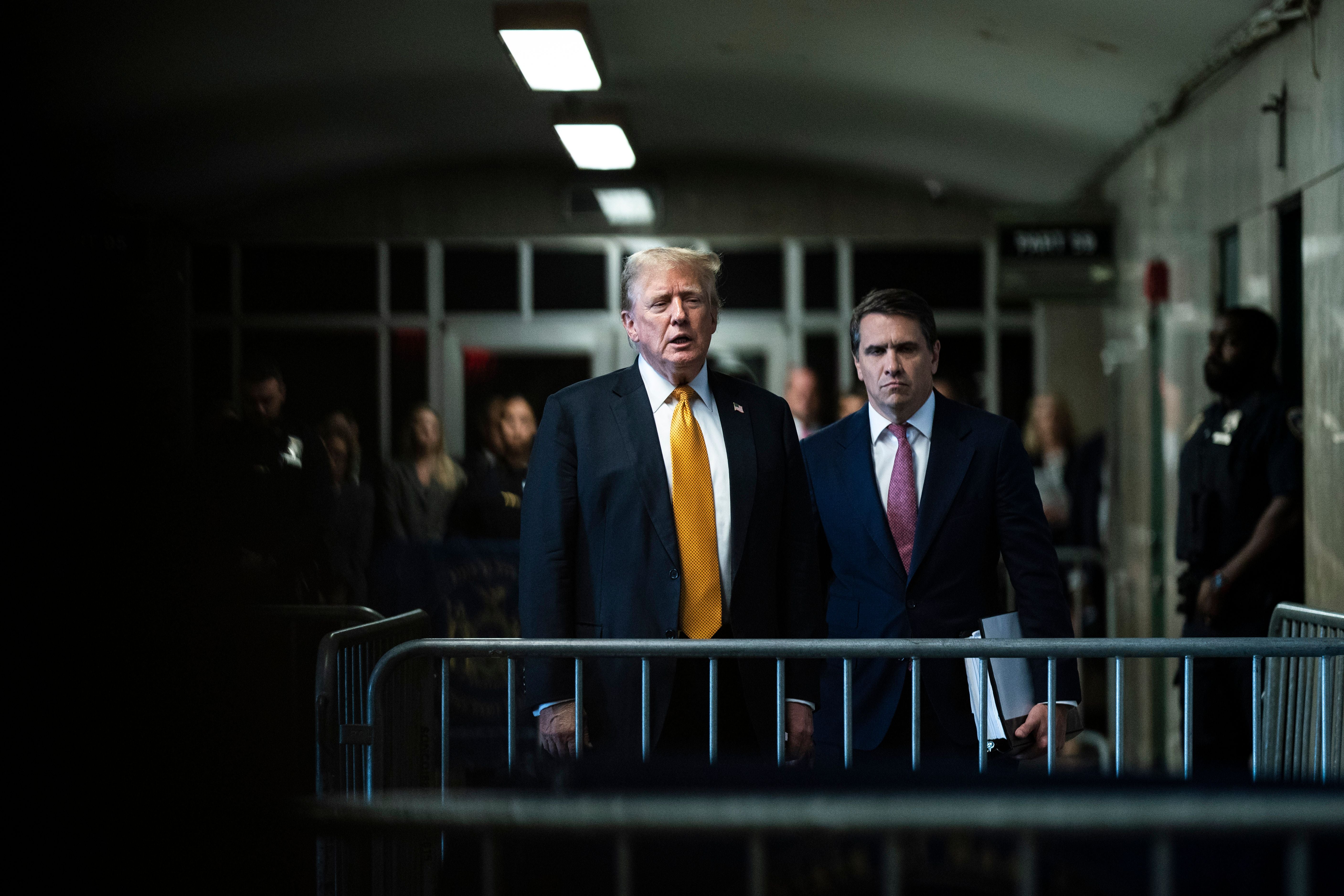 Donald Trump und ein Anwalt stehen hinter Absperrungen in einem Gerichtsgebäude in New York.