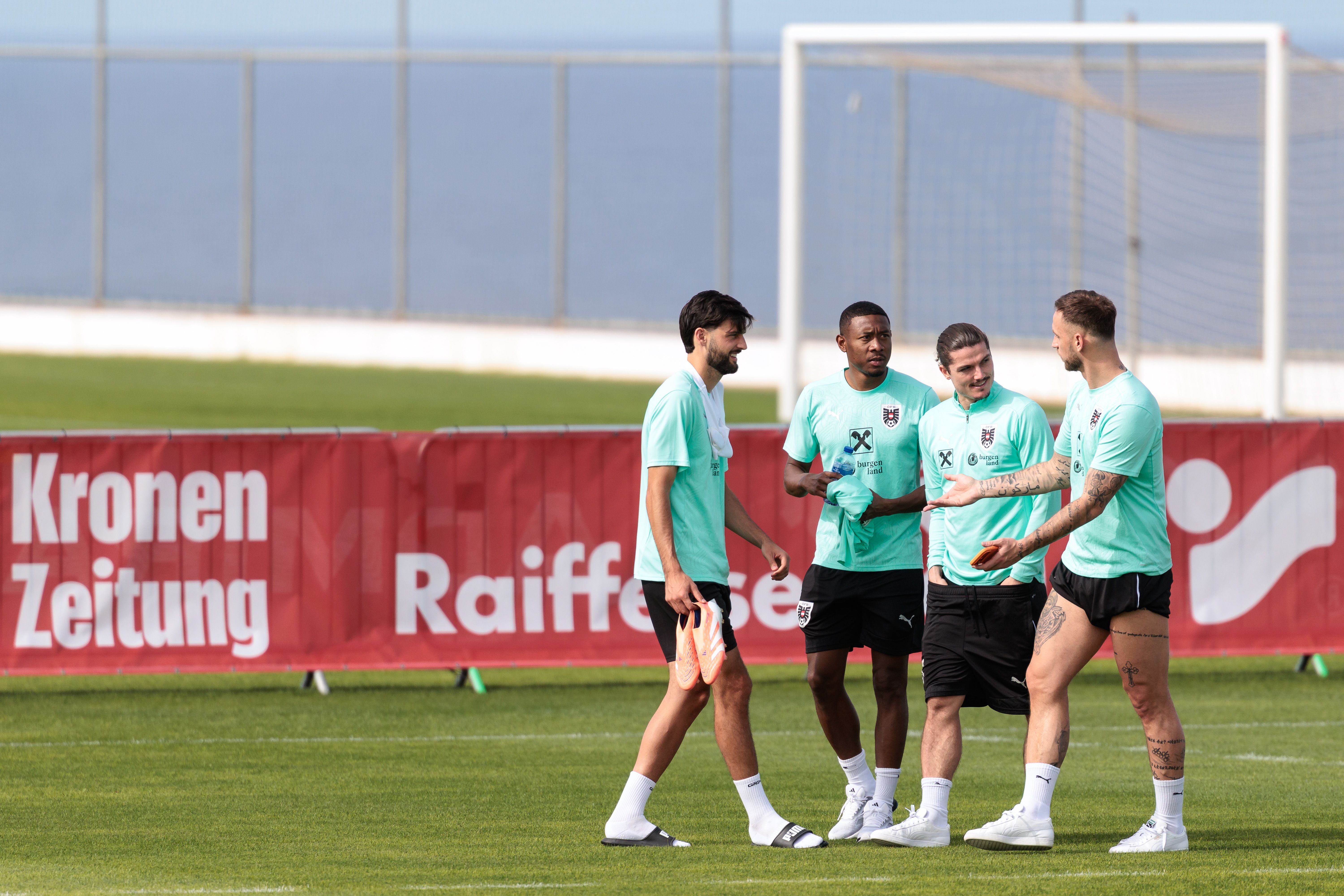 Vier österreichische Fußballspieler sprechen bei einem Training auf dem Spielfeld miteinander.