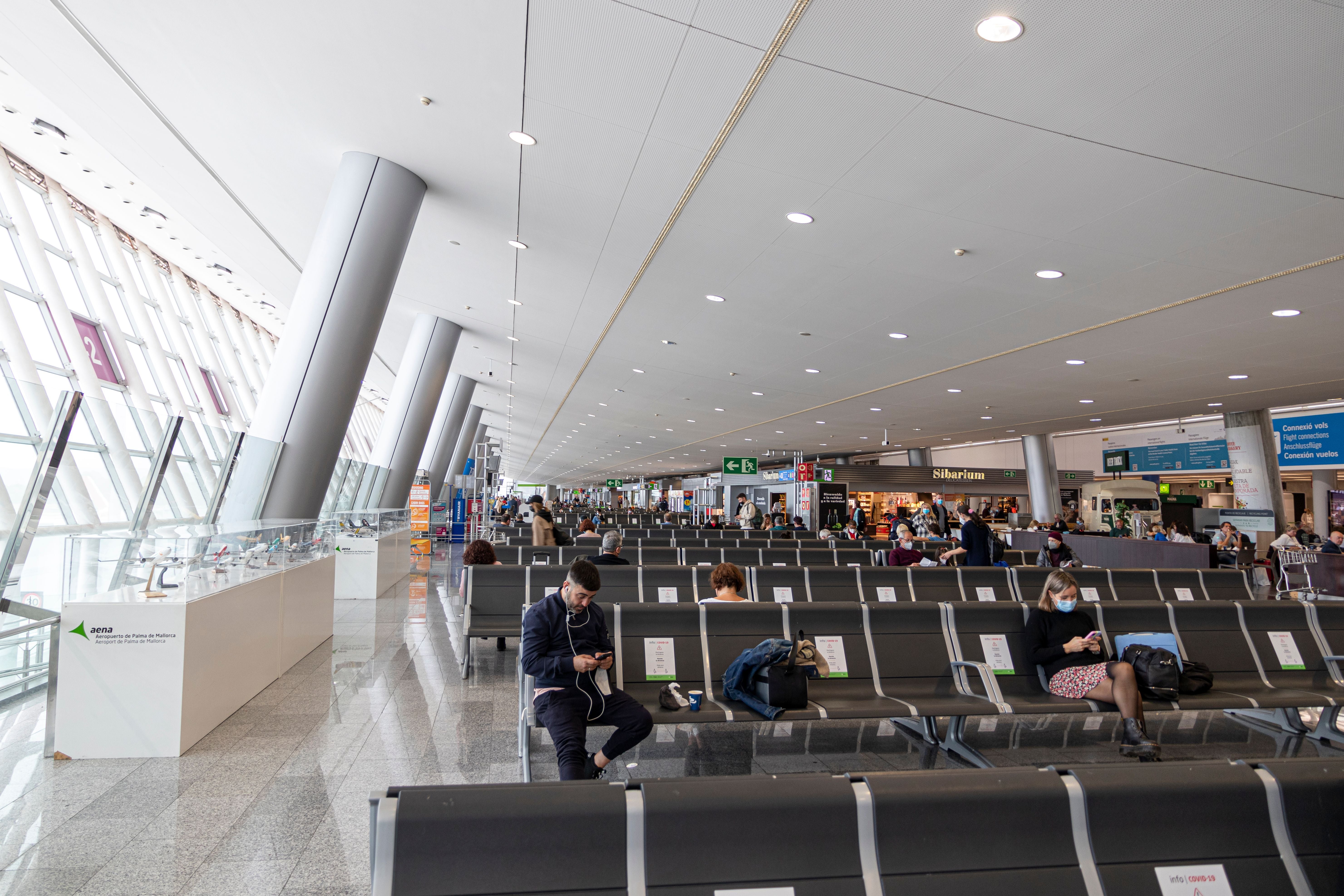 Menschen sitzen und warten auf Sitzreihen im modernen Flughafen Palma de Mallorca.