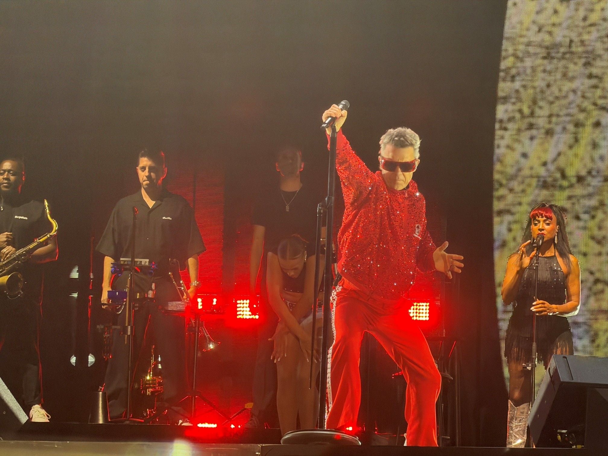 Robbie Williams tritt in rotem Glitzer-Outfit mit Band auf einer Bühne in Bratislava auf.