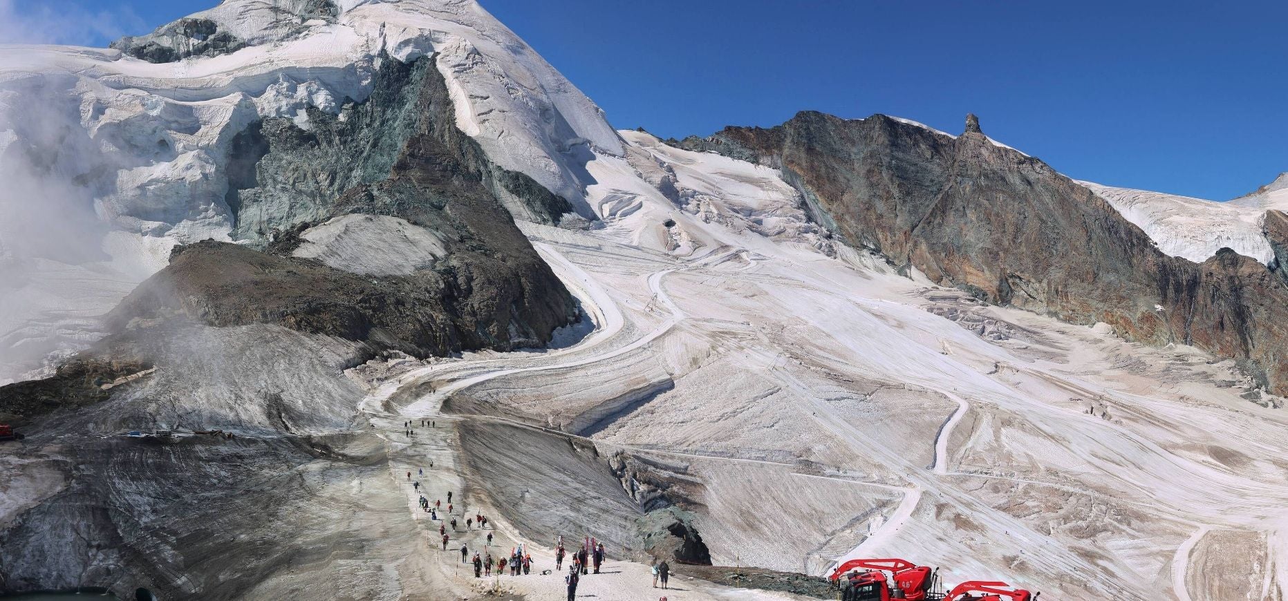 Menschen wandern auf einem verschneiten Gletscher bei Saas-Fee in den Schweizer Alpen.