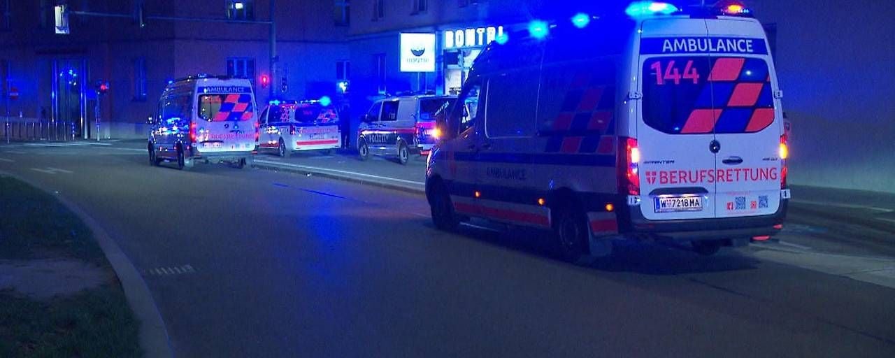 Mehrere Rettungs- und Polizeifahrzeuge mit Blaulicht vor einem Krankenhaus bei Nacht.