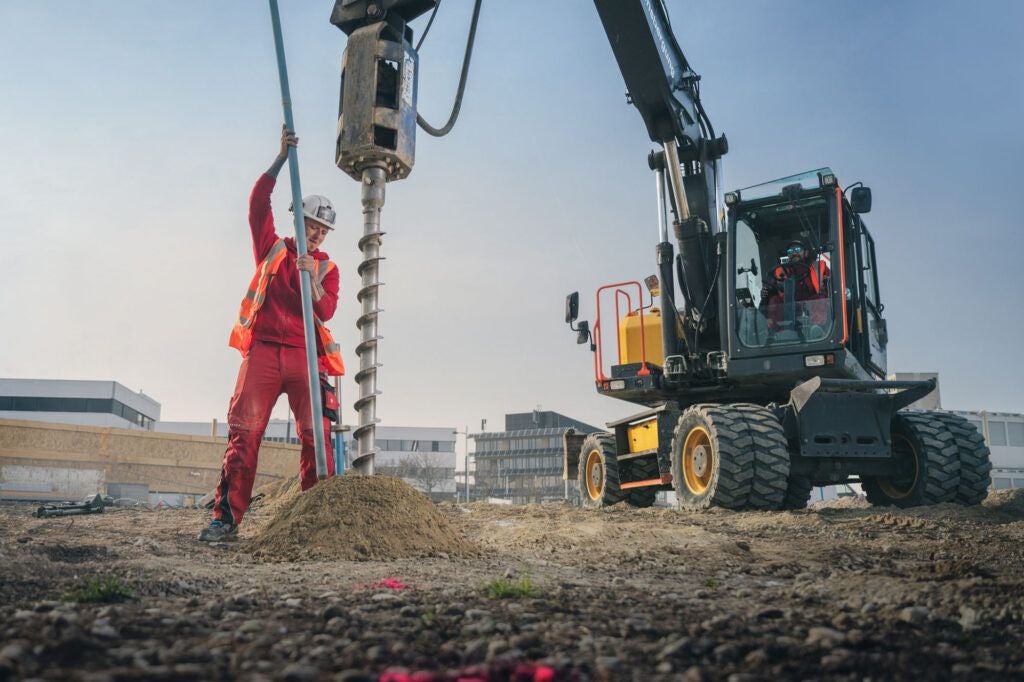 Bauarbeiter führt Bohrarbeiten mit Bagger auf einer Baustelle durch, Gefahrensituation möglich.