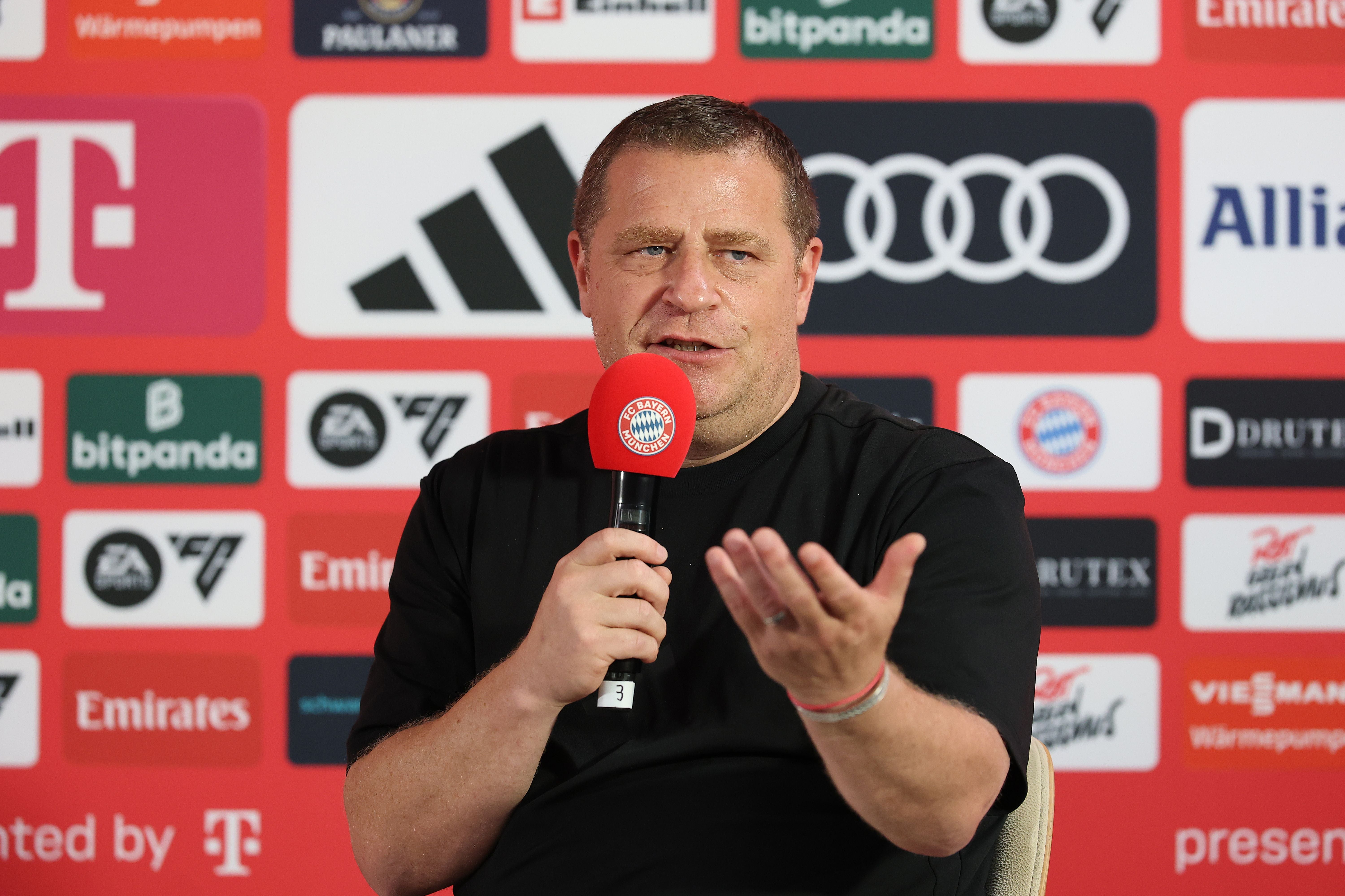 Ein Mann spricht auf einer FC Bayern München Pressekonferenz mit Mikrofon vor Sponsorenwand.